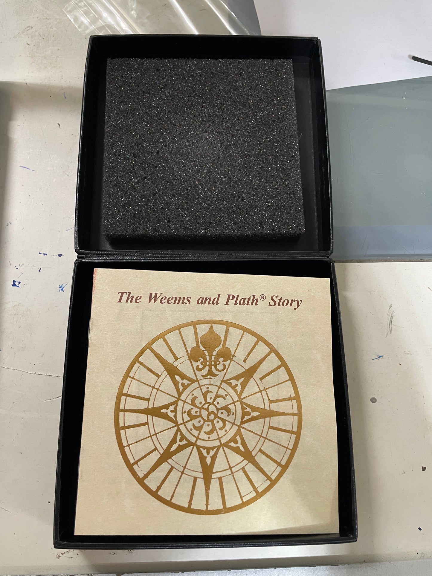 Open box with a compass design and text on a white surface