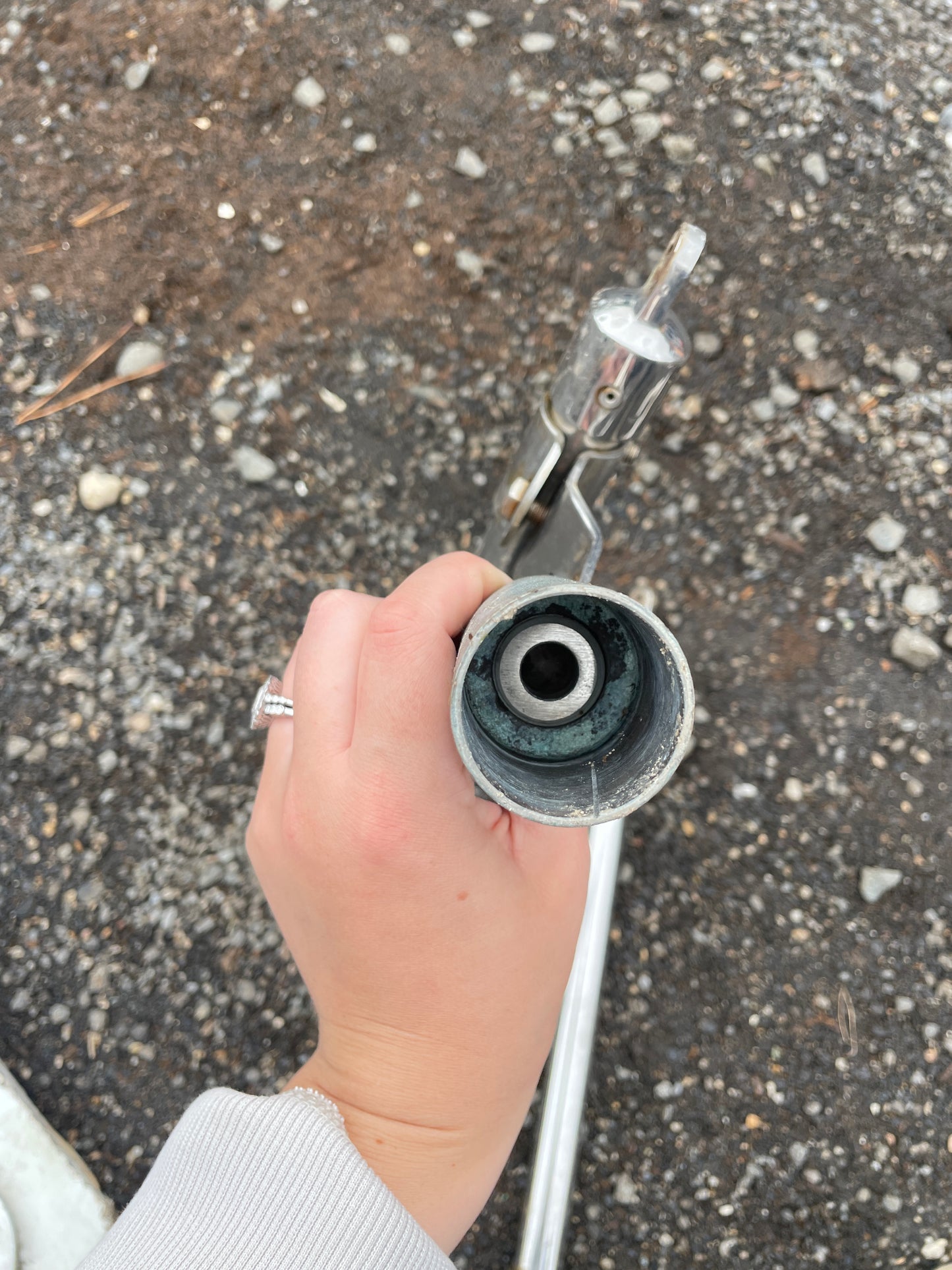 Hand holding a garden hose nozzle against a concrete background