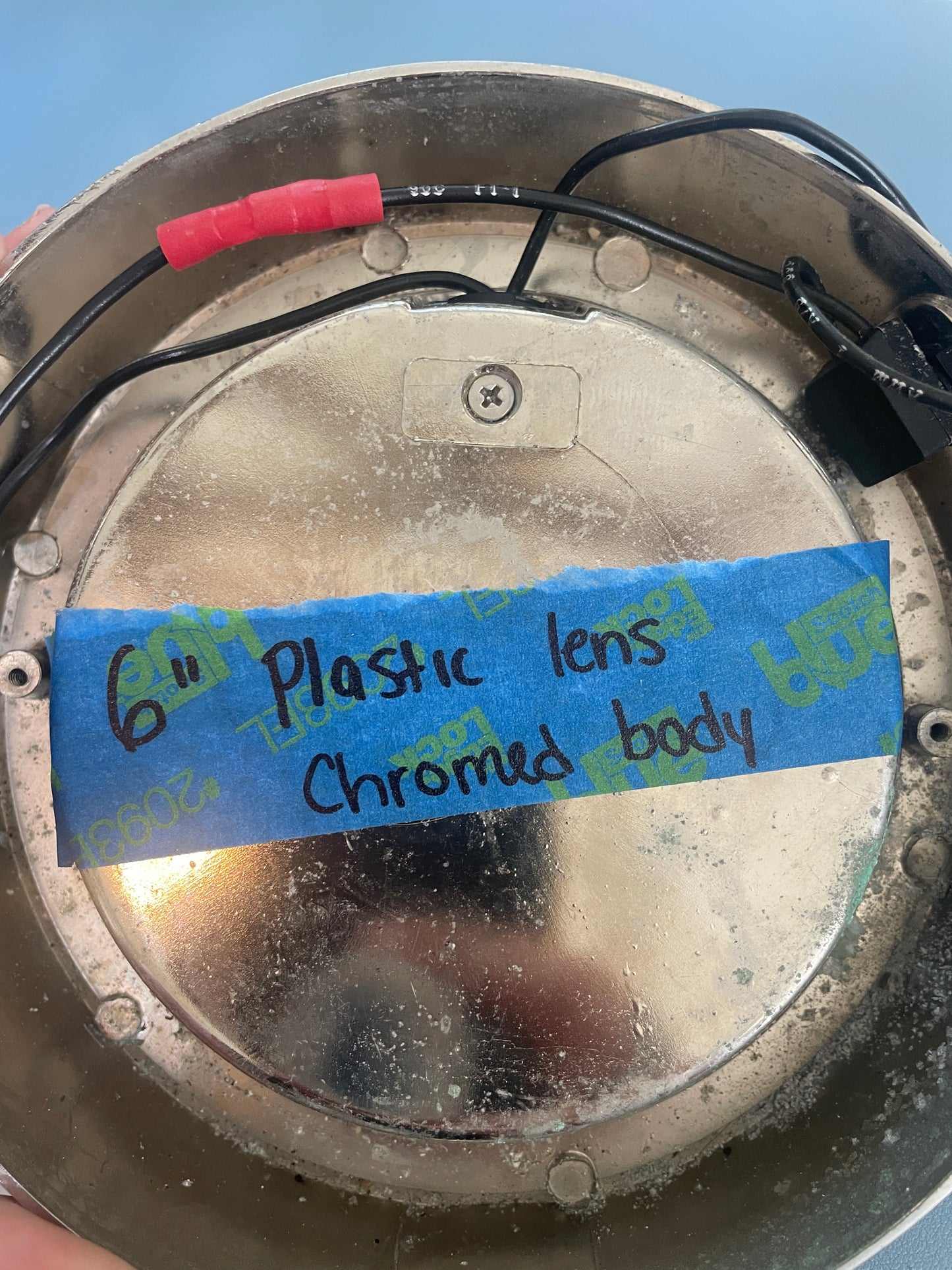 Metal component with blue tape labels indicating 'Plastic lens' and 'Chromed body'.