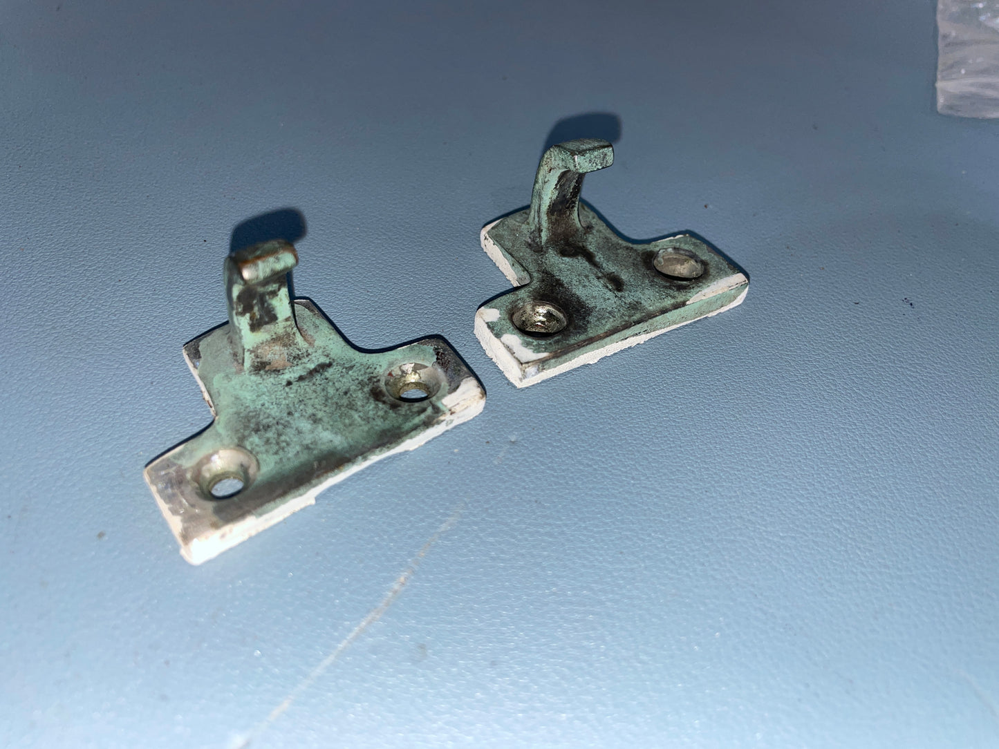 Two metal brackets on a blue surface