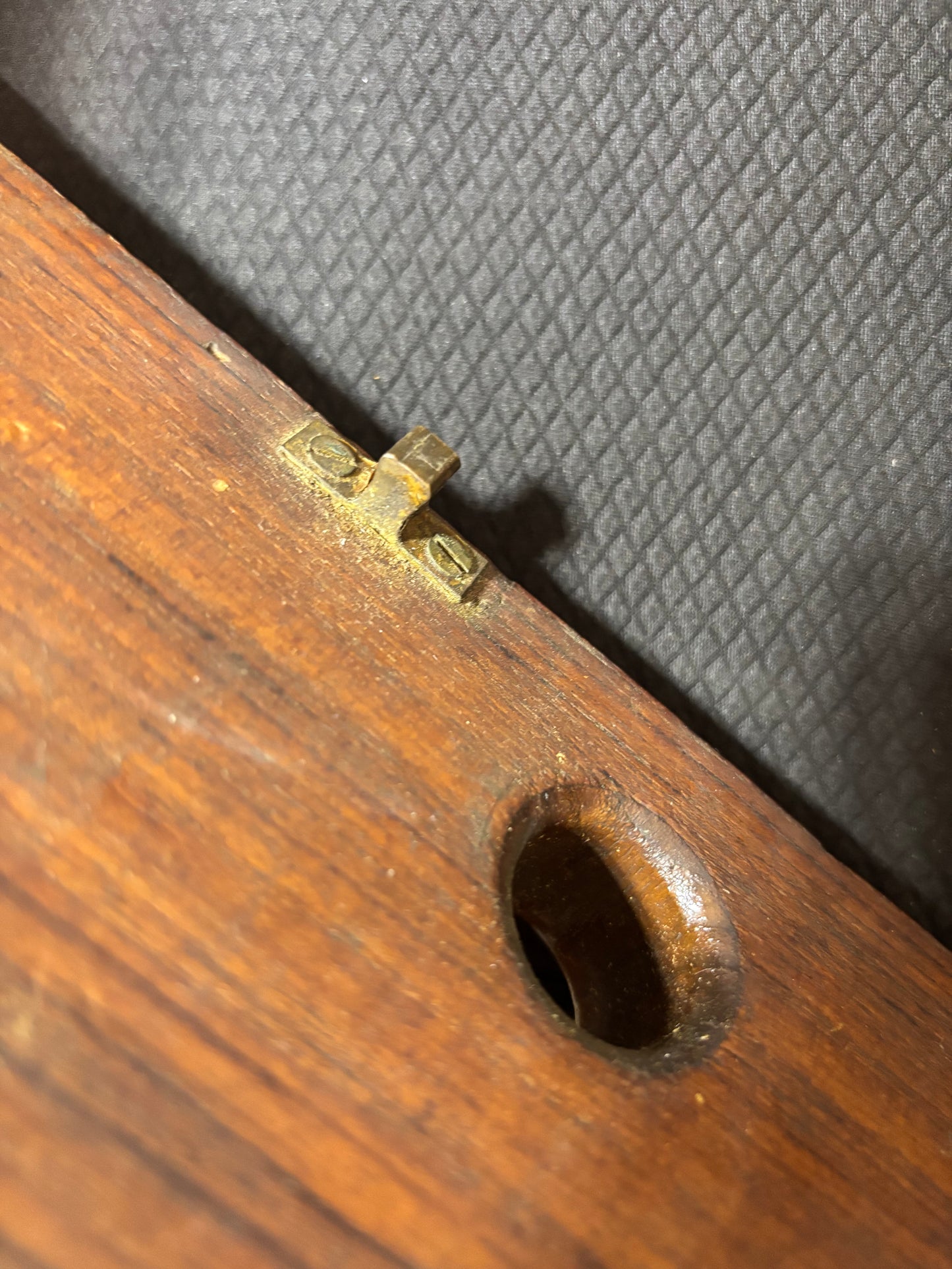 Wooden object with a metal lock mechanism on a textured gray background