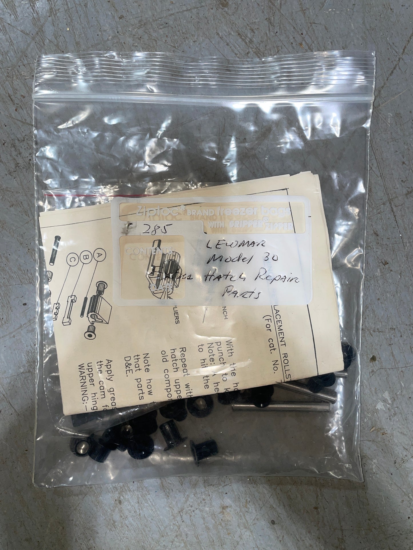 Packaged mechanical parts with instructions on a gray surface