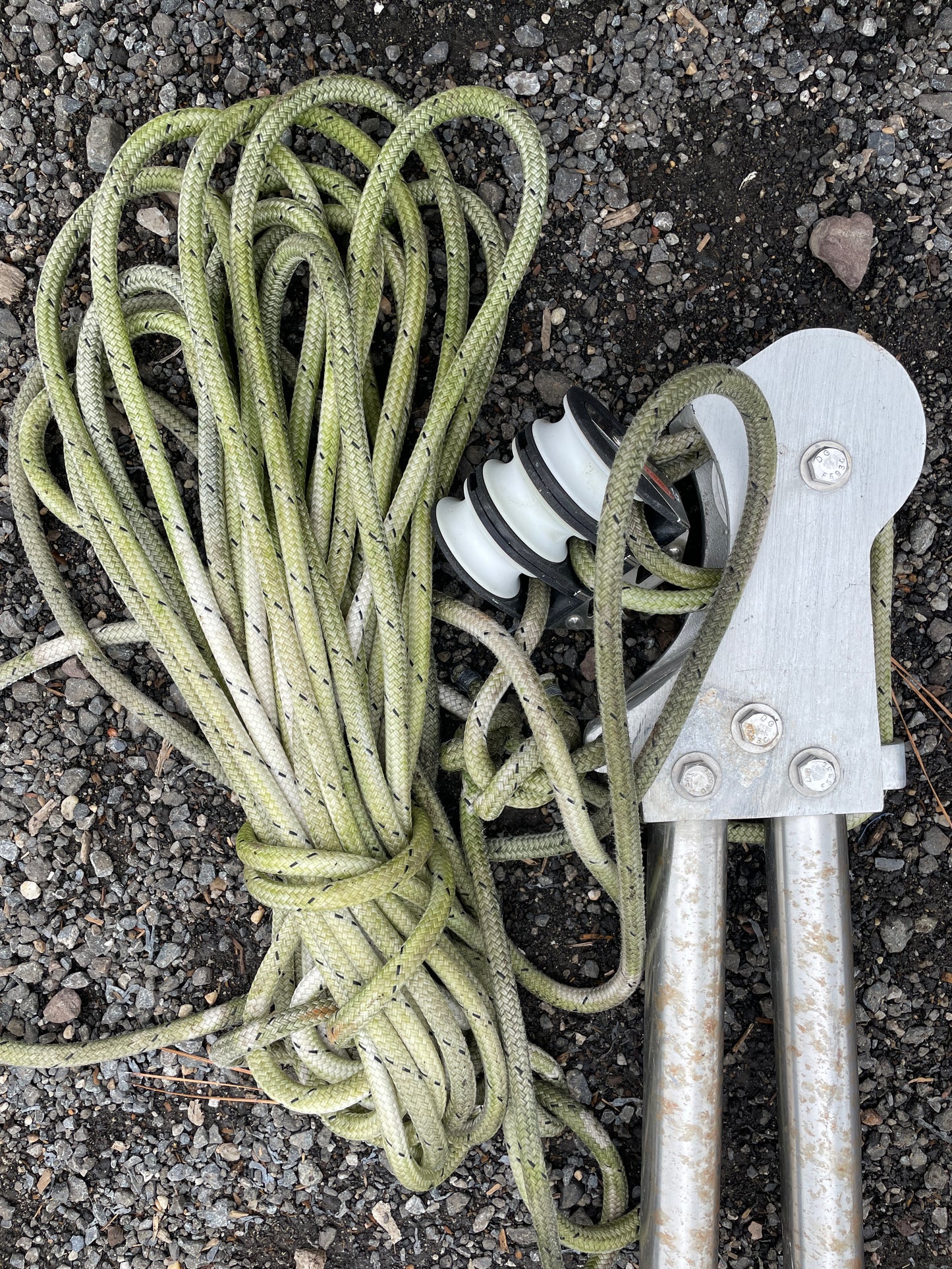 Coiled green rope with a metal tool on a dark surface