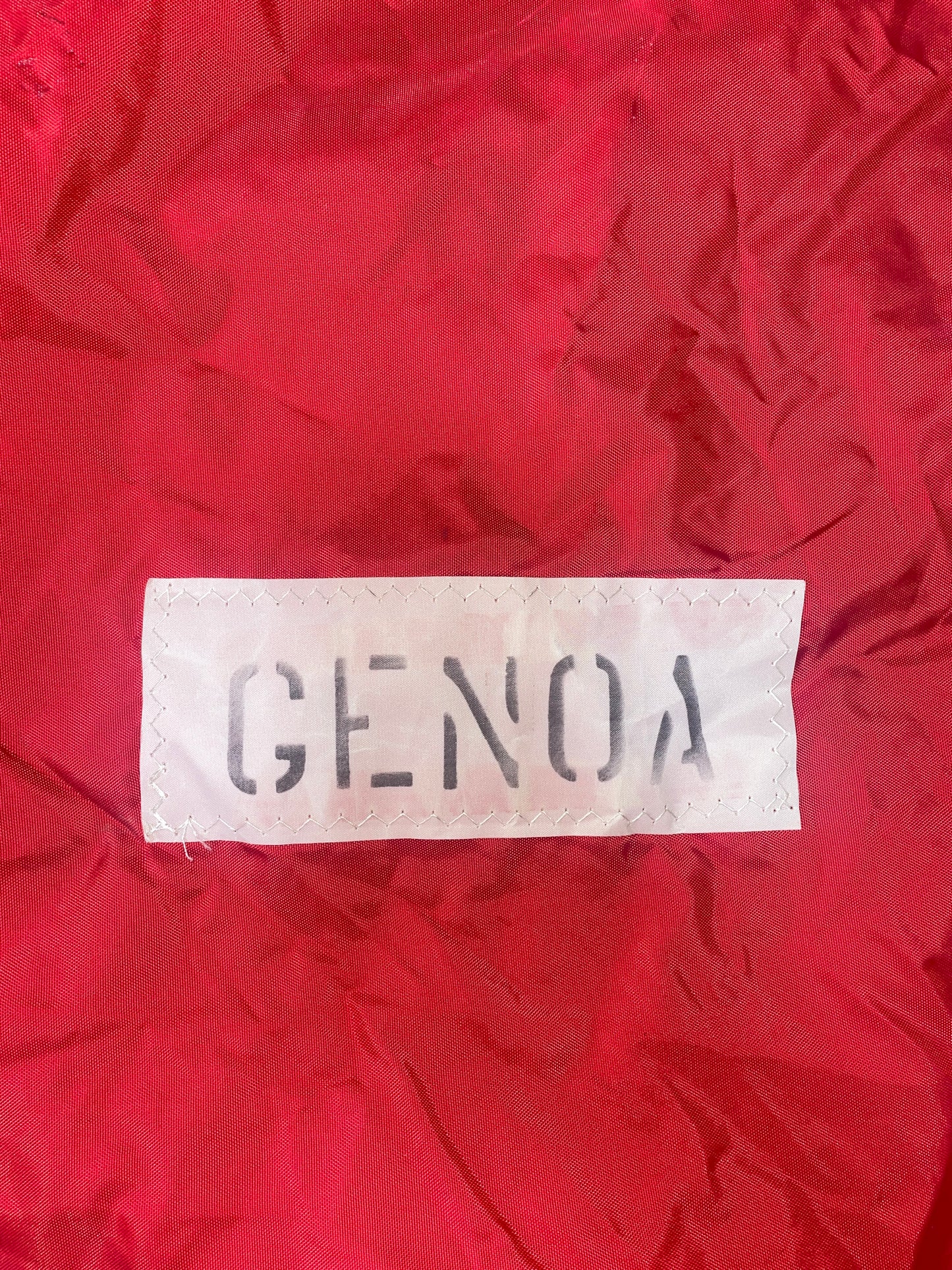 Red fabric with a white label displaying 'GENOA' on a red background