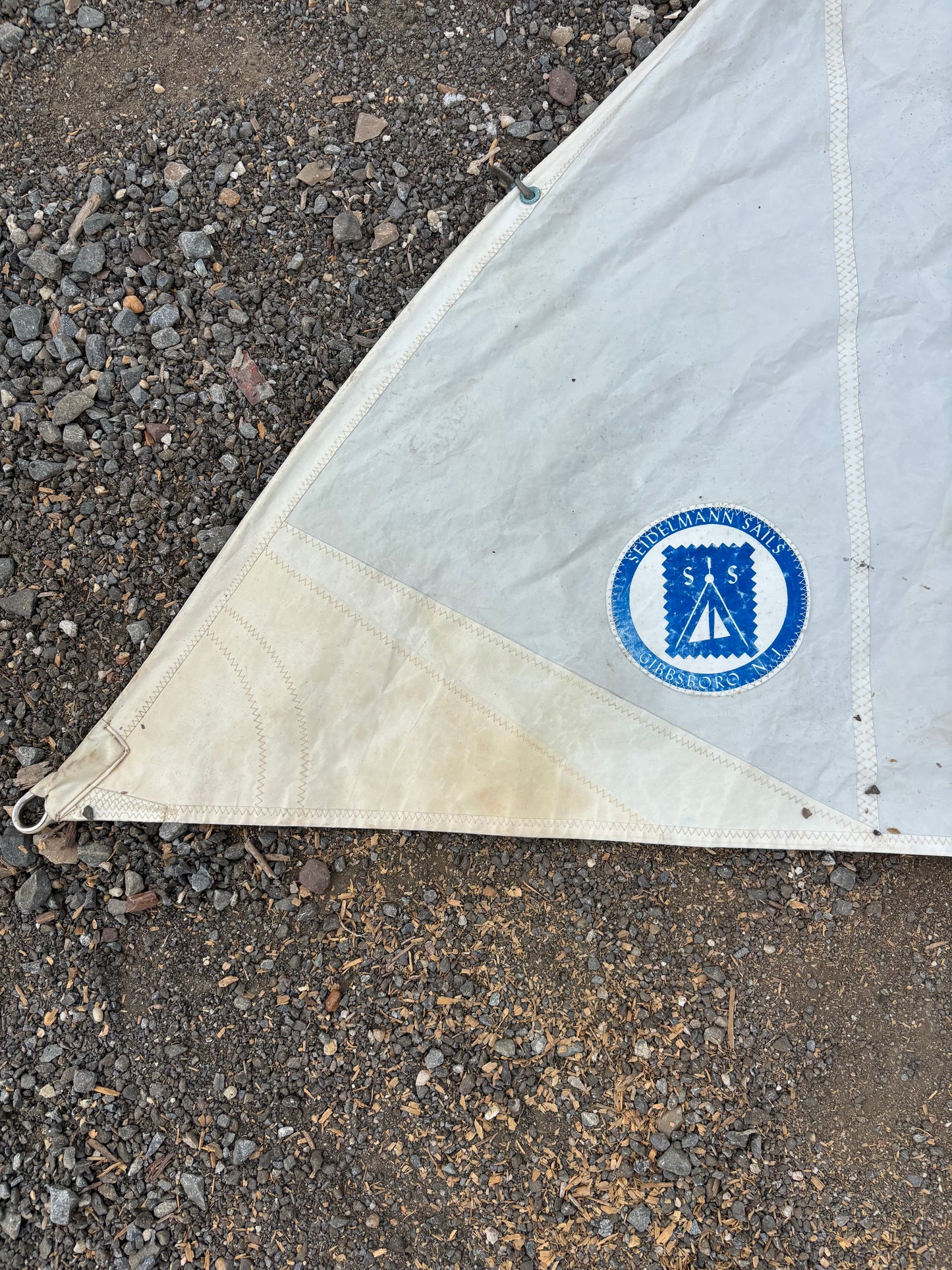 White tarp with a blue logo on a gravel surface