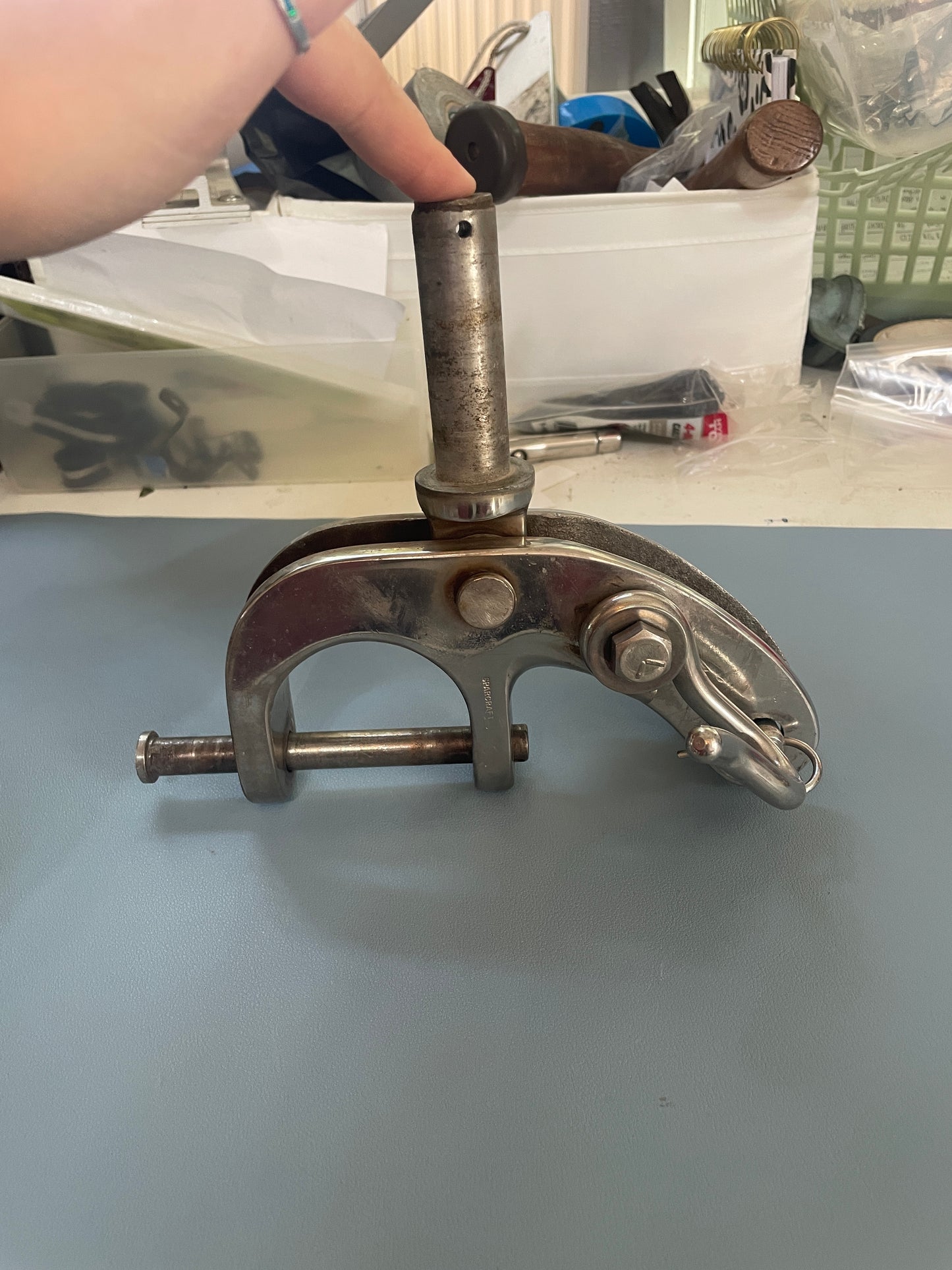 Metal clamp on a light blue wall with tools and equipment in the background