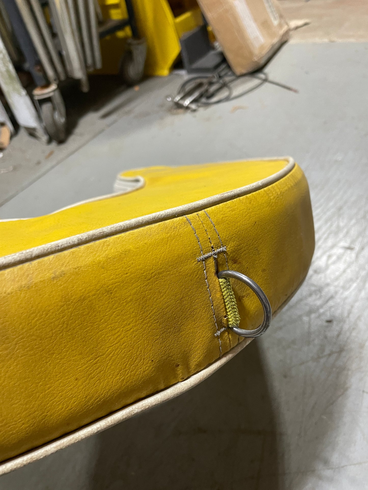 Close-up of a yellow leather seat with a metal clip on a vehicle interior.