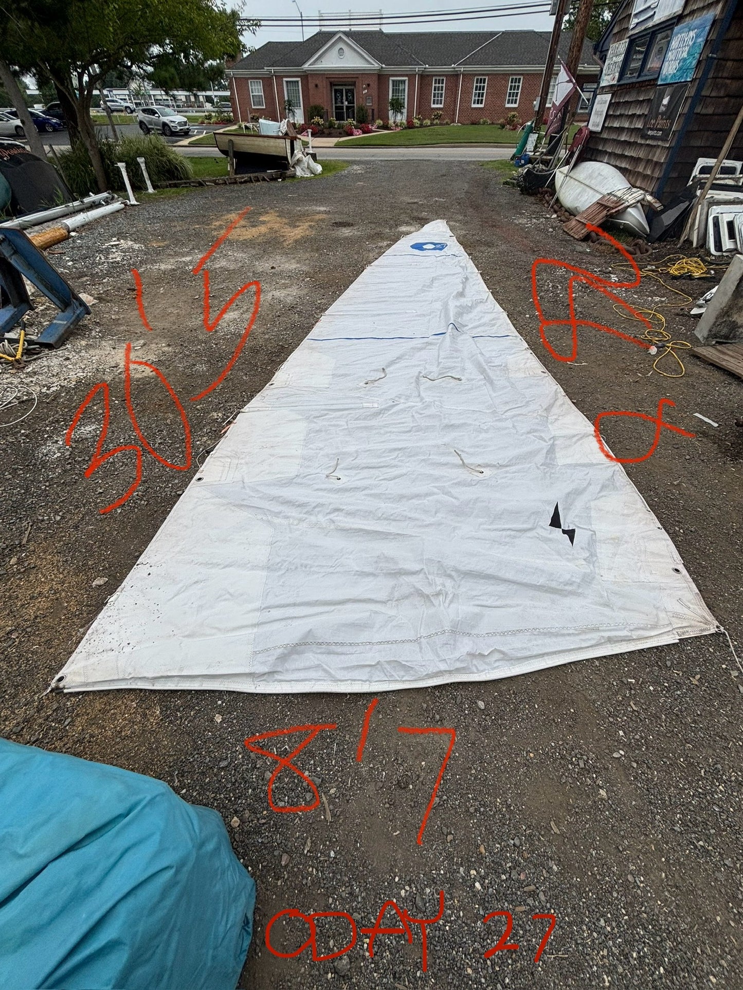 White sail on a gravel surface with red markings and a building in the background