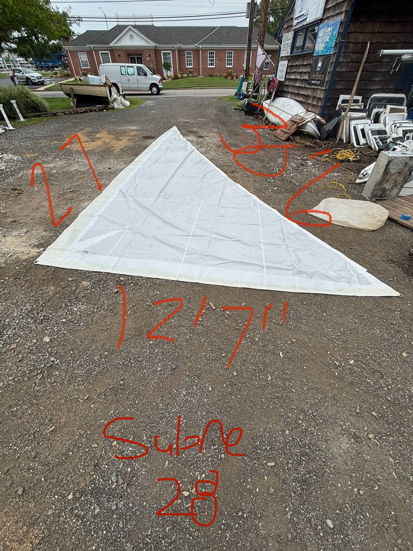 White triangle-shaped object on a gravel surface with measurements written on it.