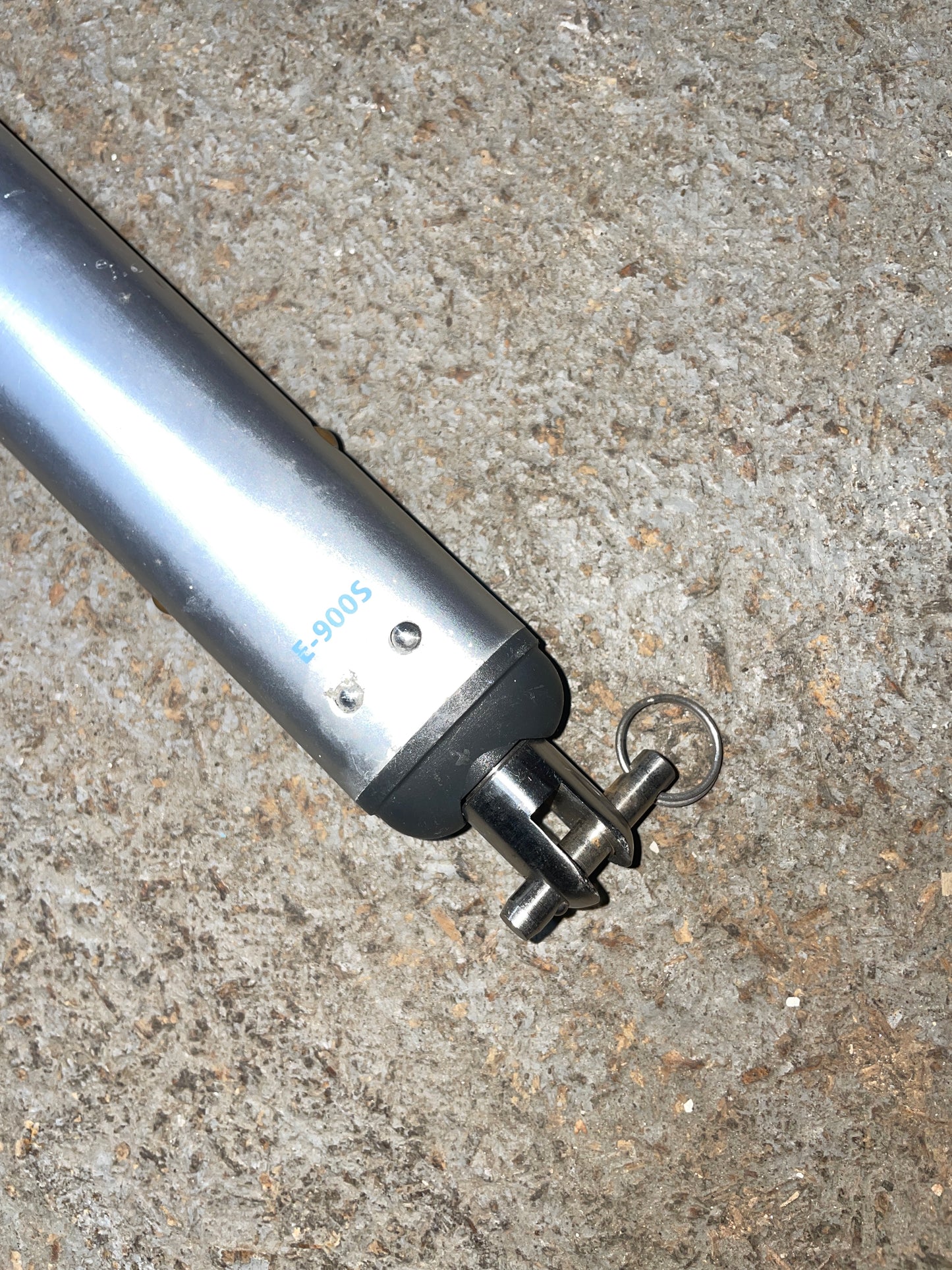 Silver cylindrical tool with a key-like attachment on a concrete surface