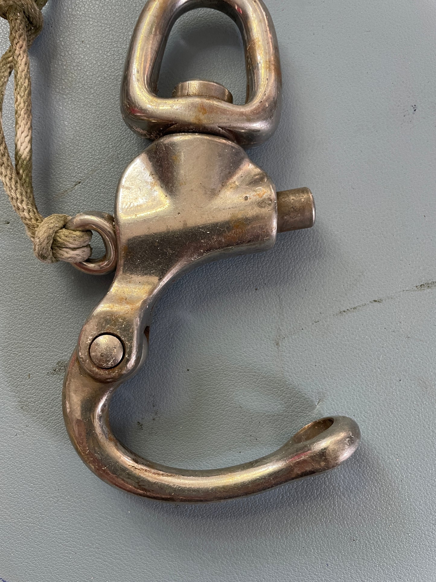 Brass snap shackle with a rope on a gray background