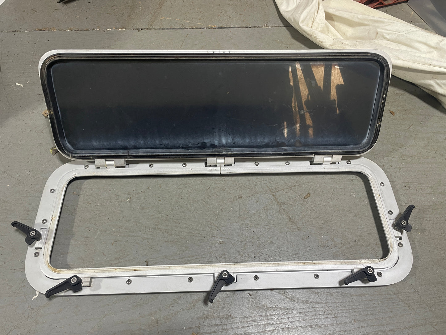 Open metal window frame with glass on a gray surface