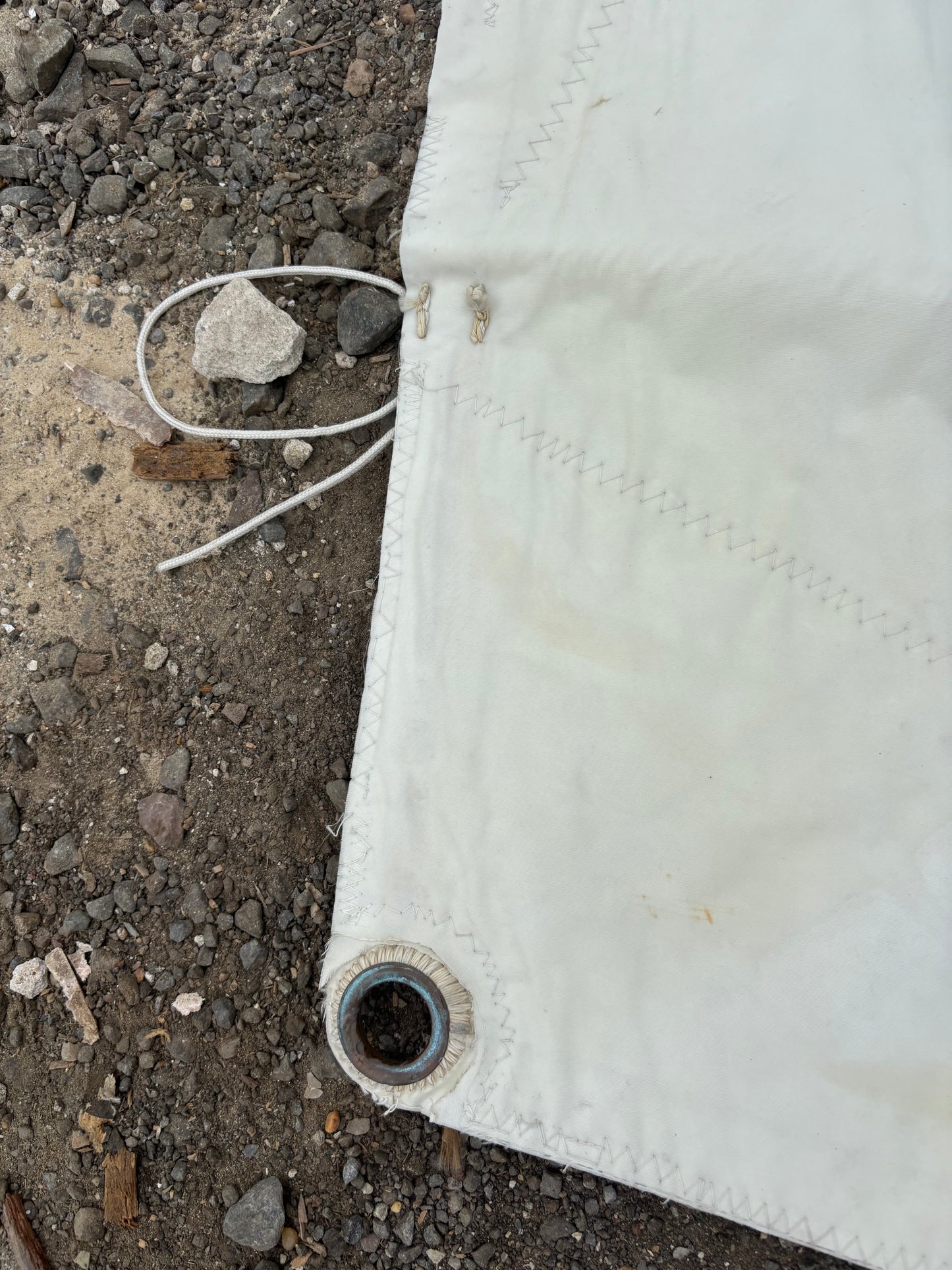 White tarp on a concrete surface with visible stitching and a knot.