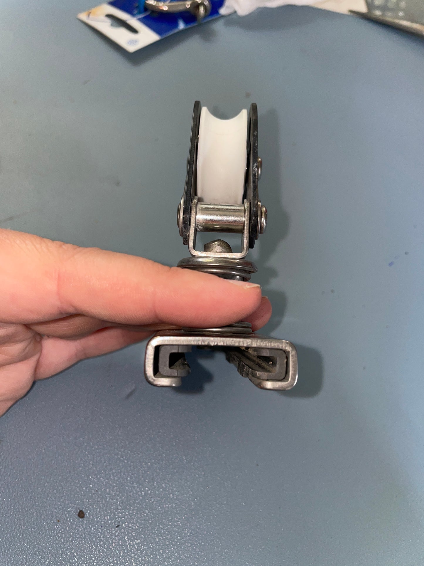 Hand holding a metal door hinge against a gray background