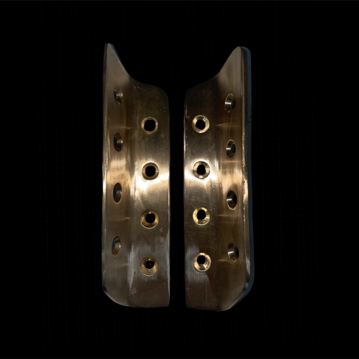 Pair of metallic protective guards with multiple holes on a black background
