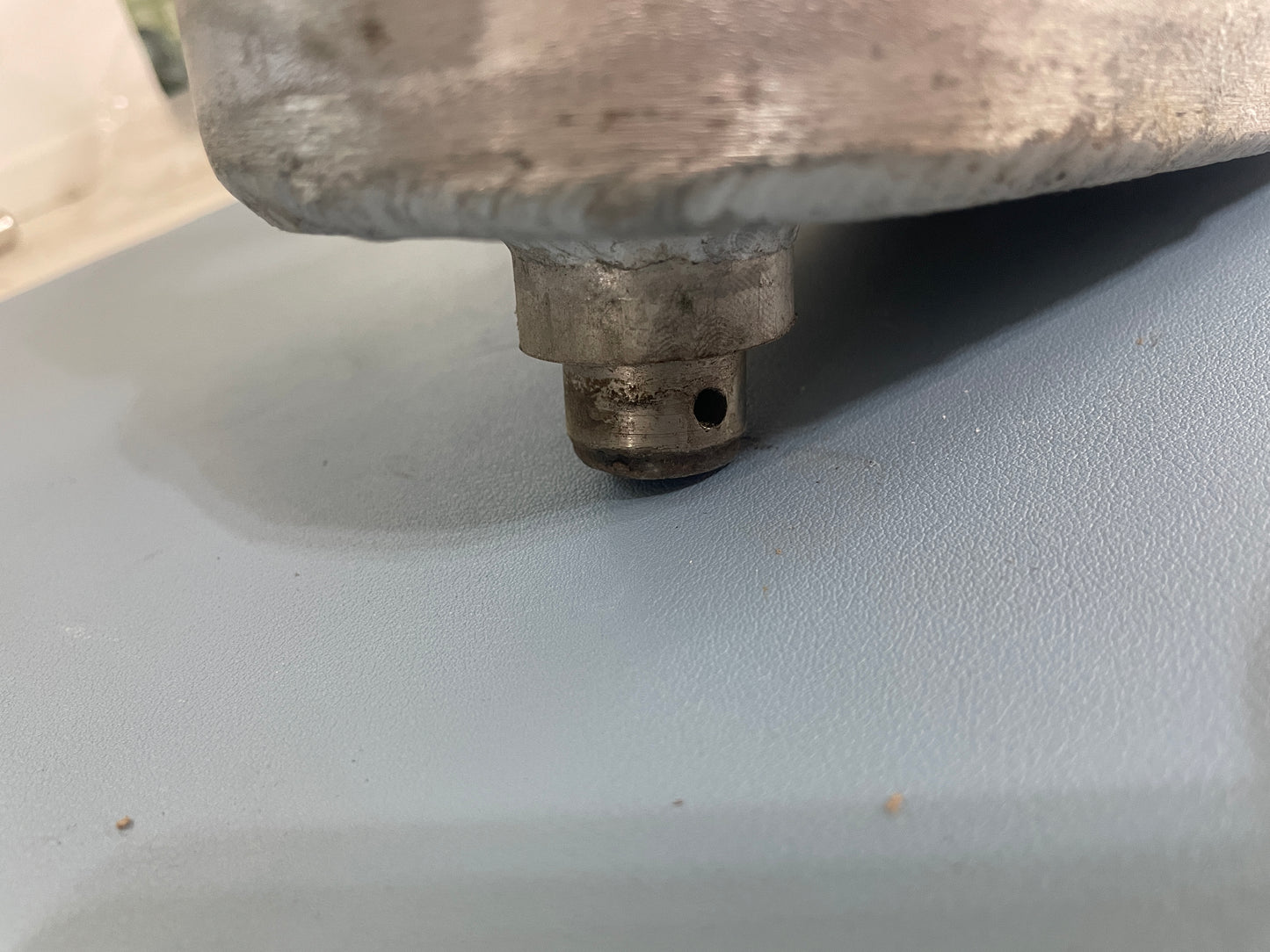 Metallic object with a cylindrical component on a gray surface