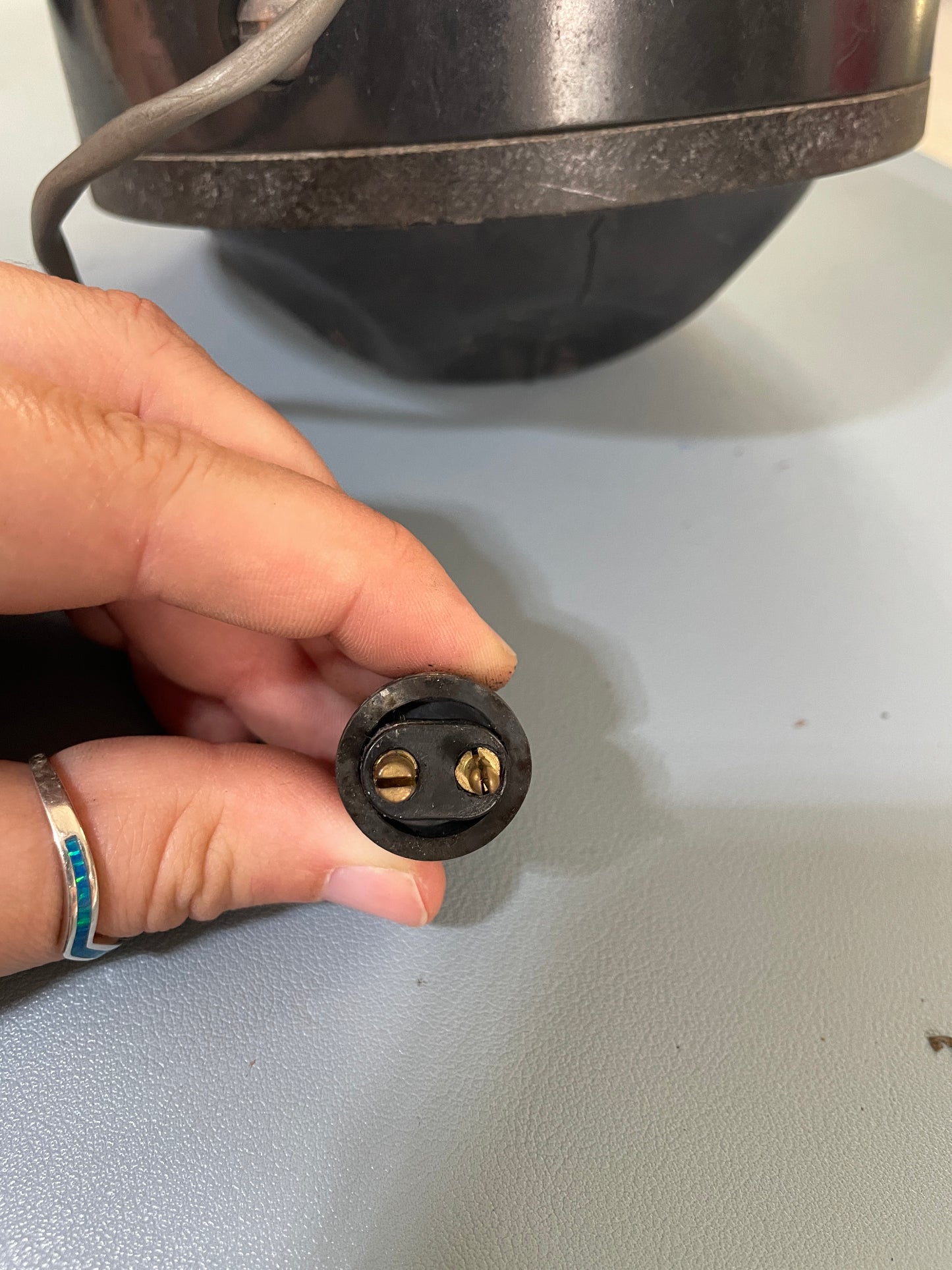 Hand holding a black electrical plug against a light gray background