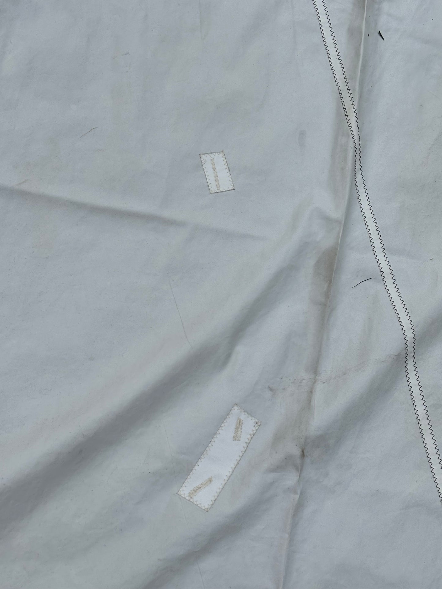 Close-up of a light gray fabric with white stitching and labels.