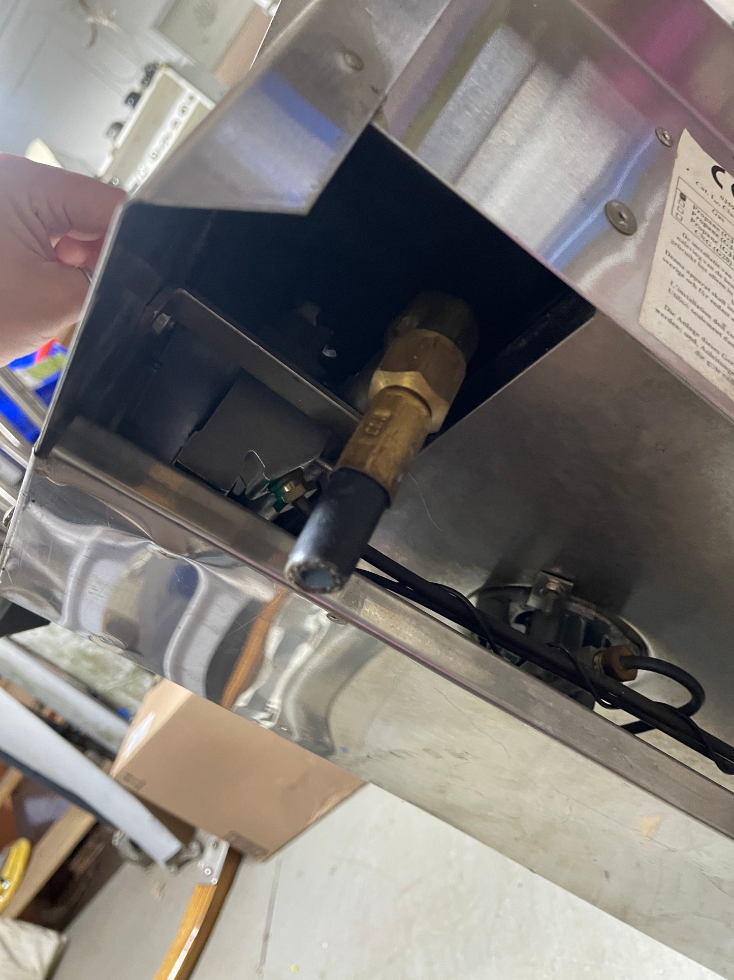 Close-up of a metallic appliance with a valve and wiring, likely part of a larger machine.