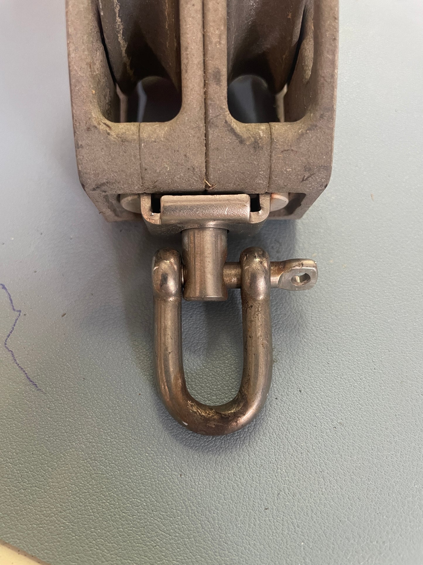 Metal shackle attached to a metal frame on a light gray background