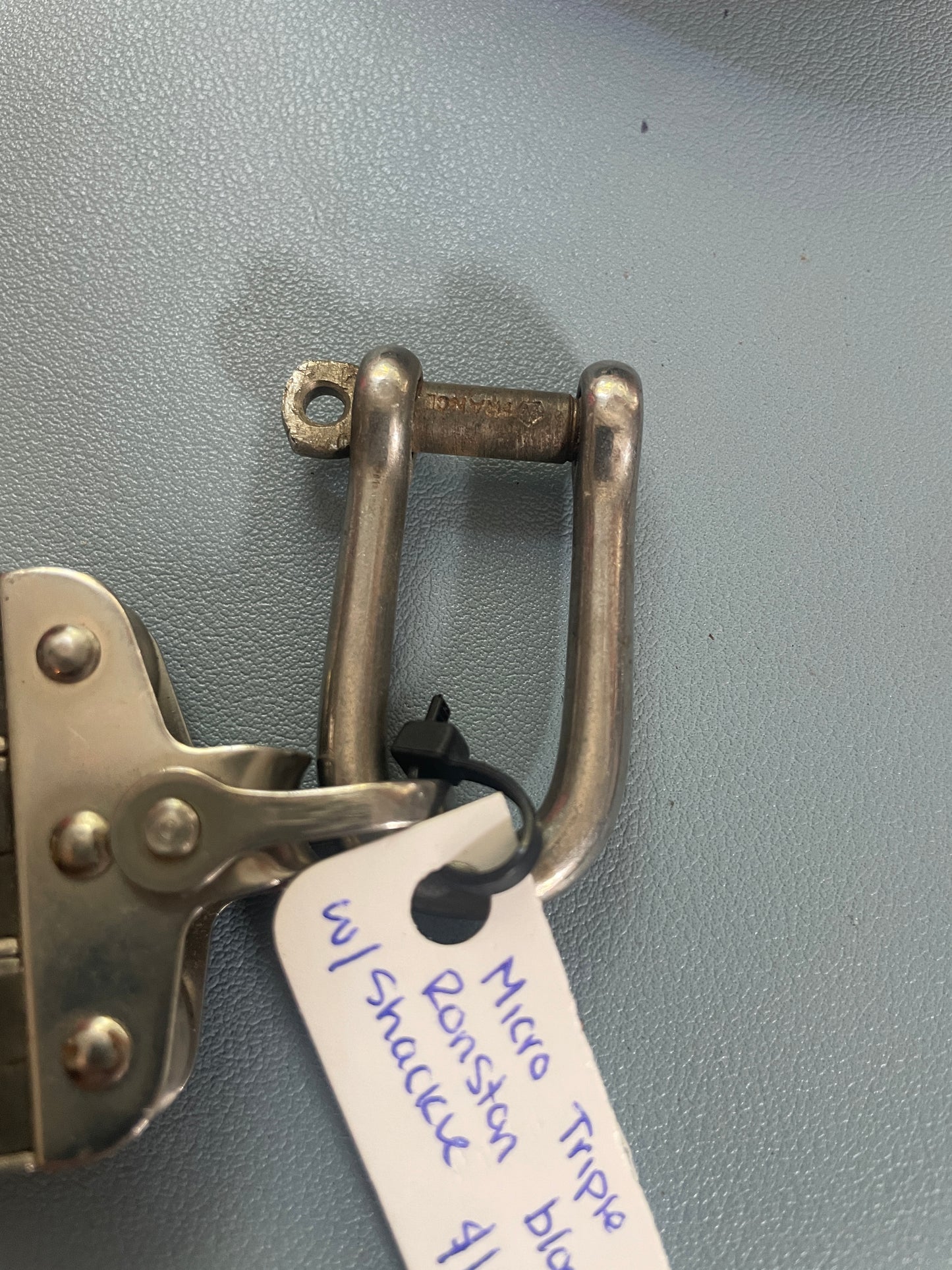 Metal clip with a tag labeled 'Micro Triple Ranson Ratchet' on a gray background