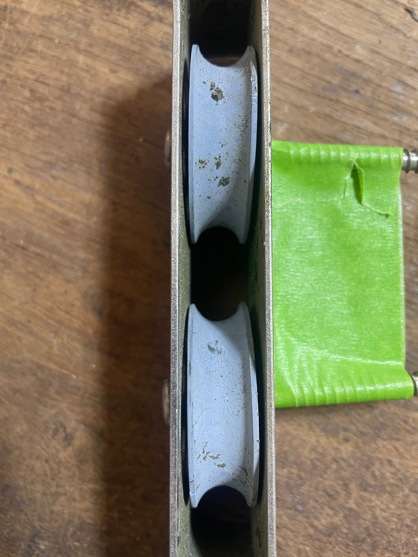 Close-up of a metal pulley system with green fabric on a wooden surface