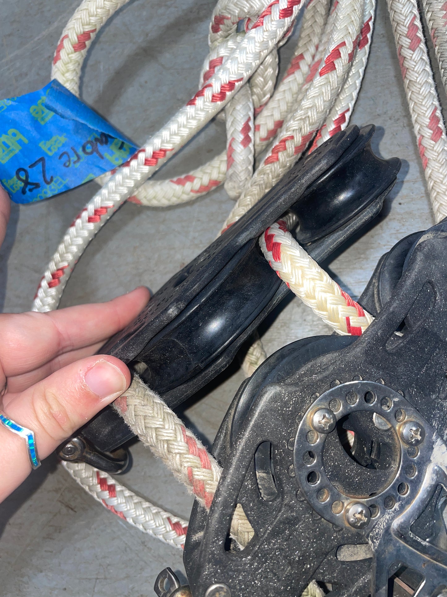Close-up of a pulley system with ropes and a hand holding it.