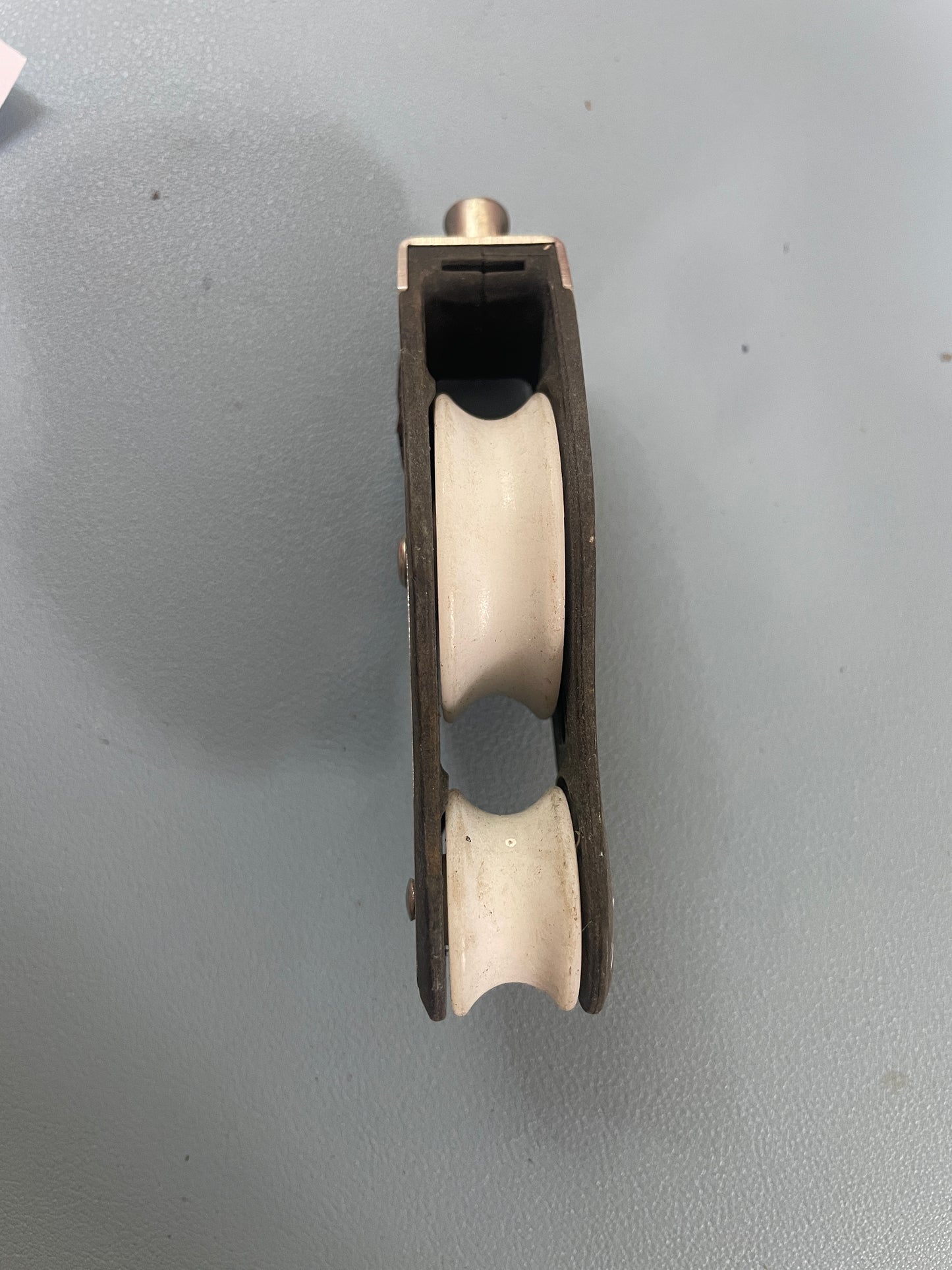 Wooden pulley system with two white rollers on a gray background