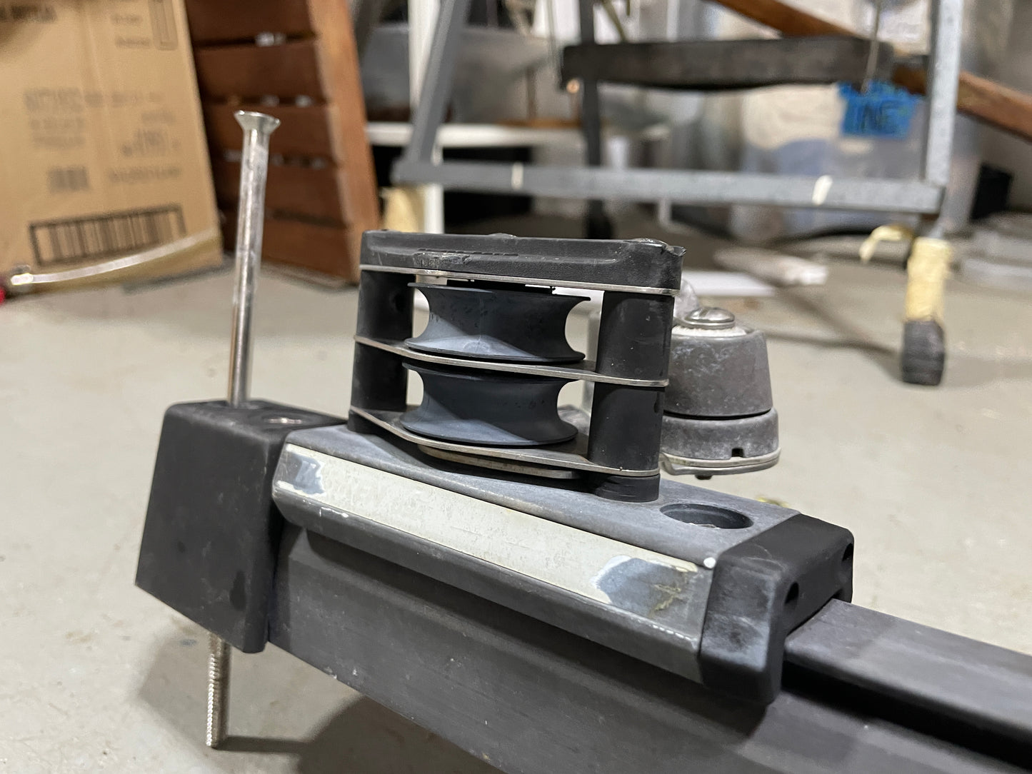 Close-up of a mechanical component on a workshop floor with tools and equipment in the background.