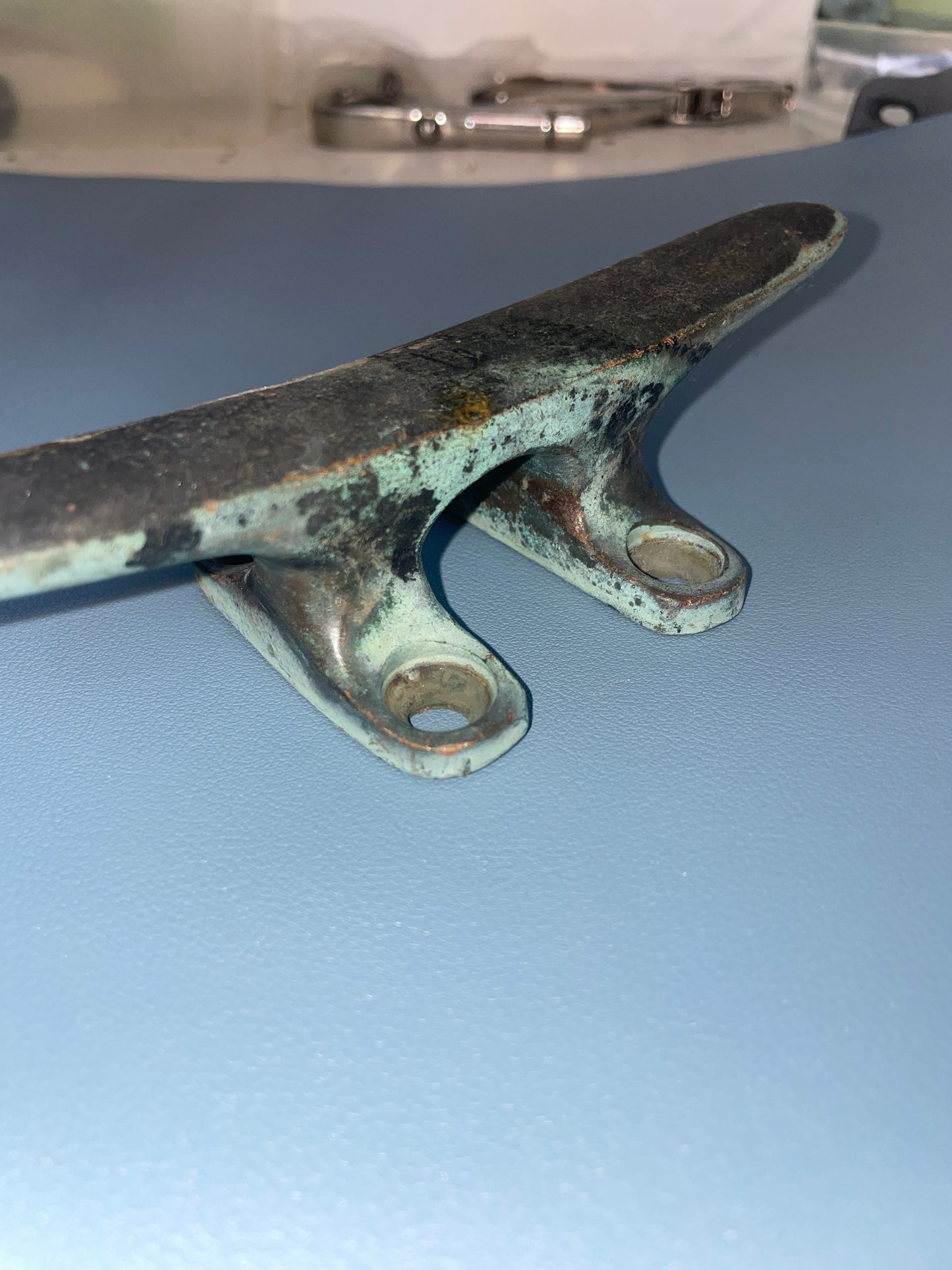 Metal clip with greenish patina on a gray background
