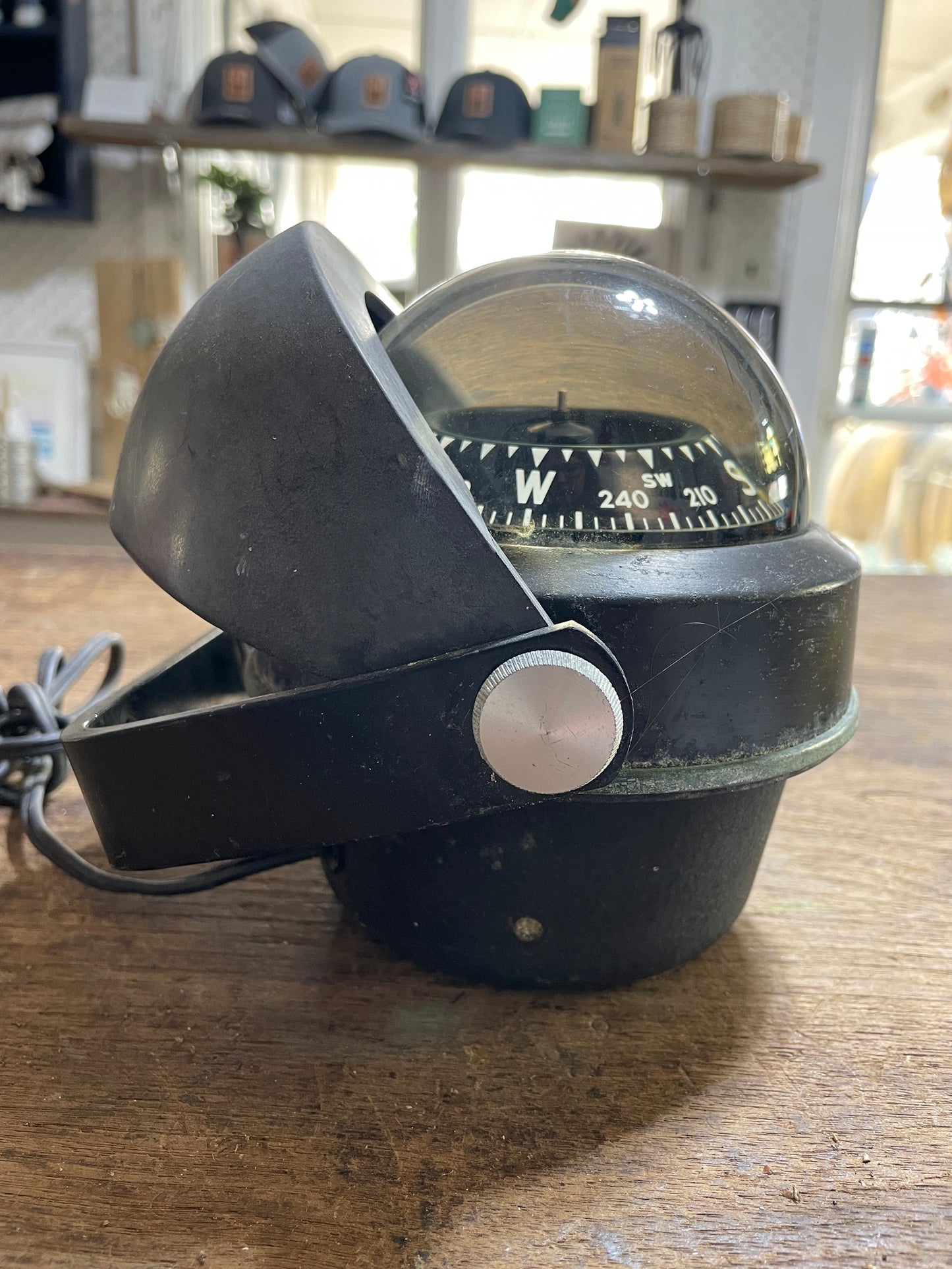 Vintage-style compass mounted on a wooden surface with blurred background