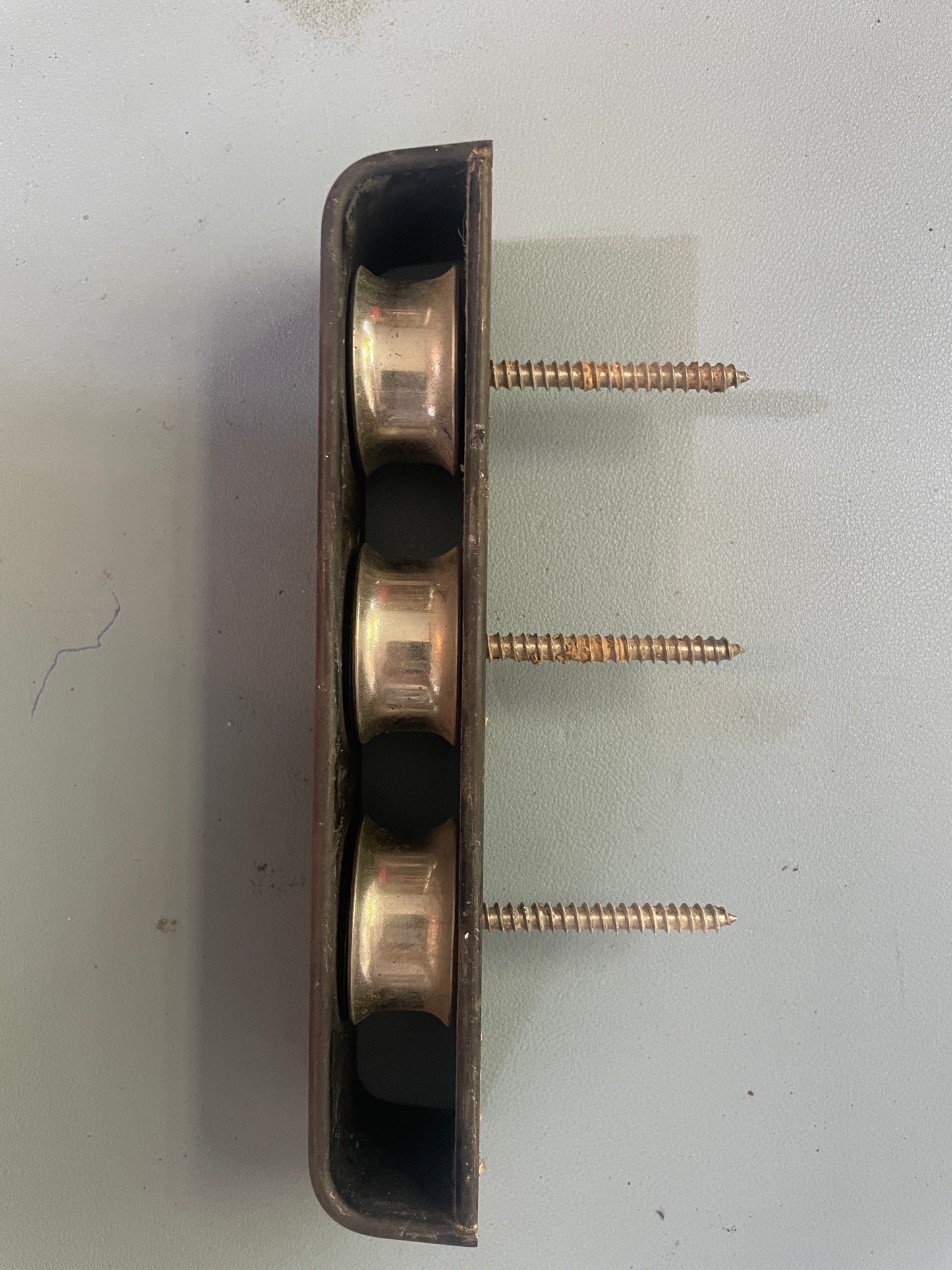 Metal bracket with three screws on a light gray background