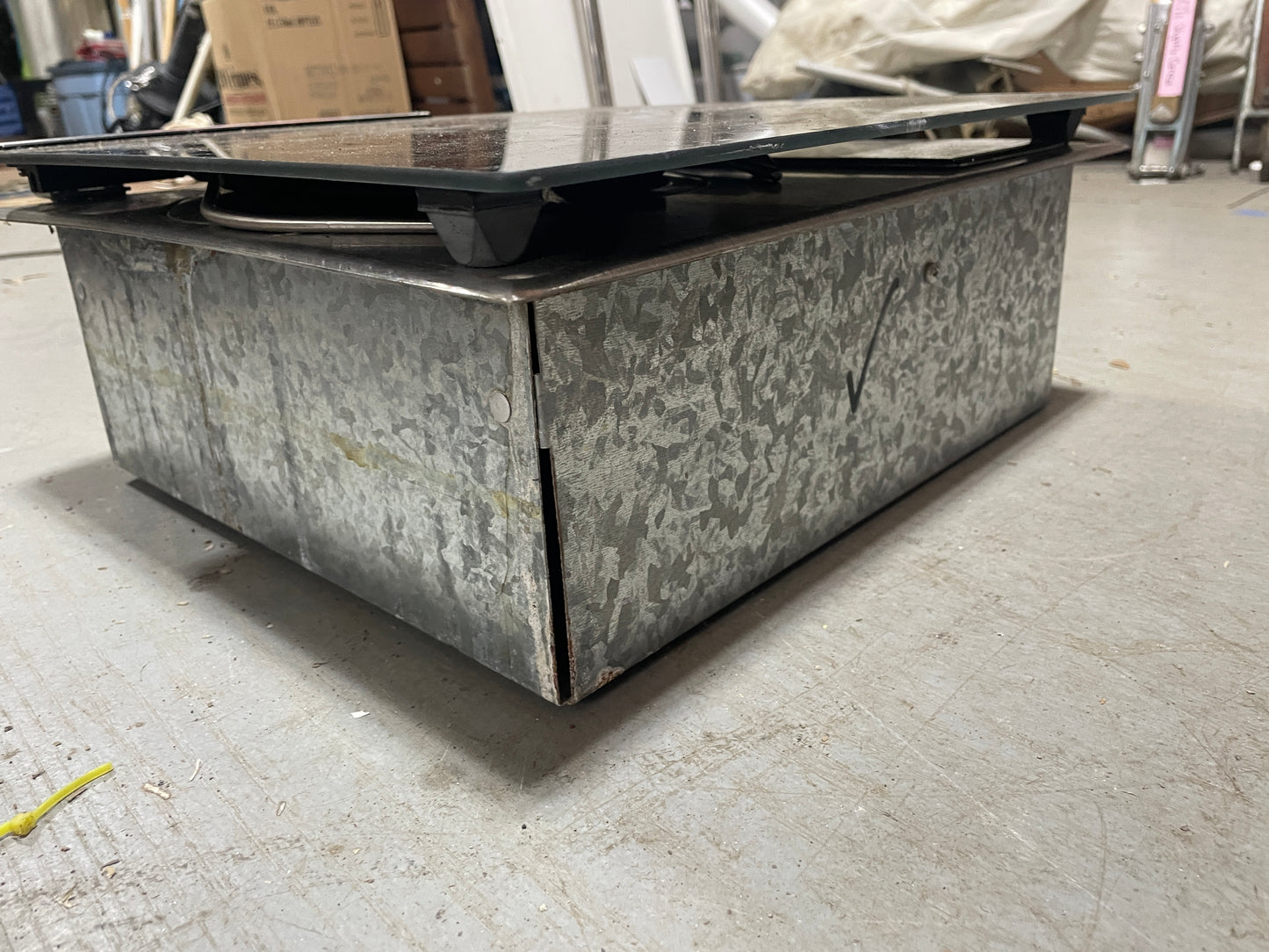 Metallic rectangular object on a concrete floor with a blurred background