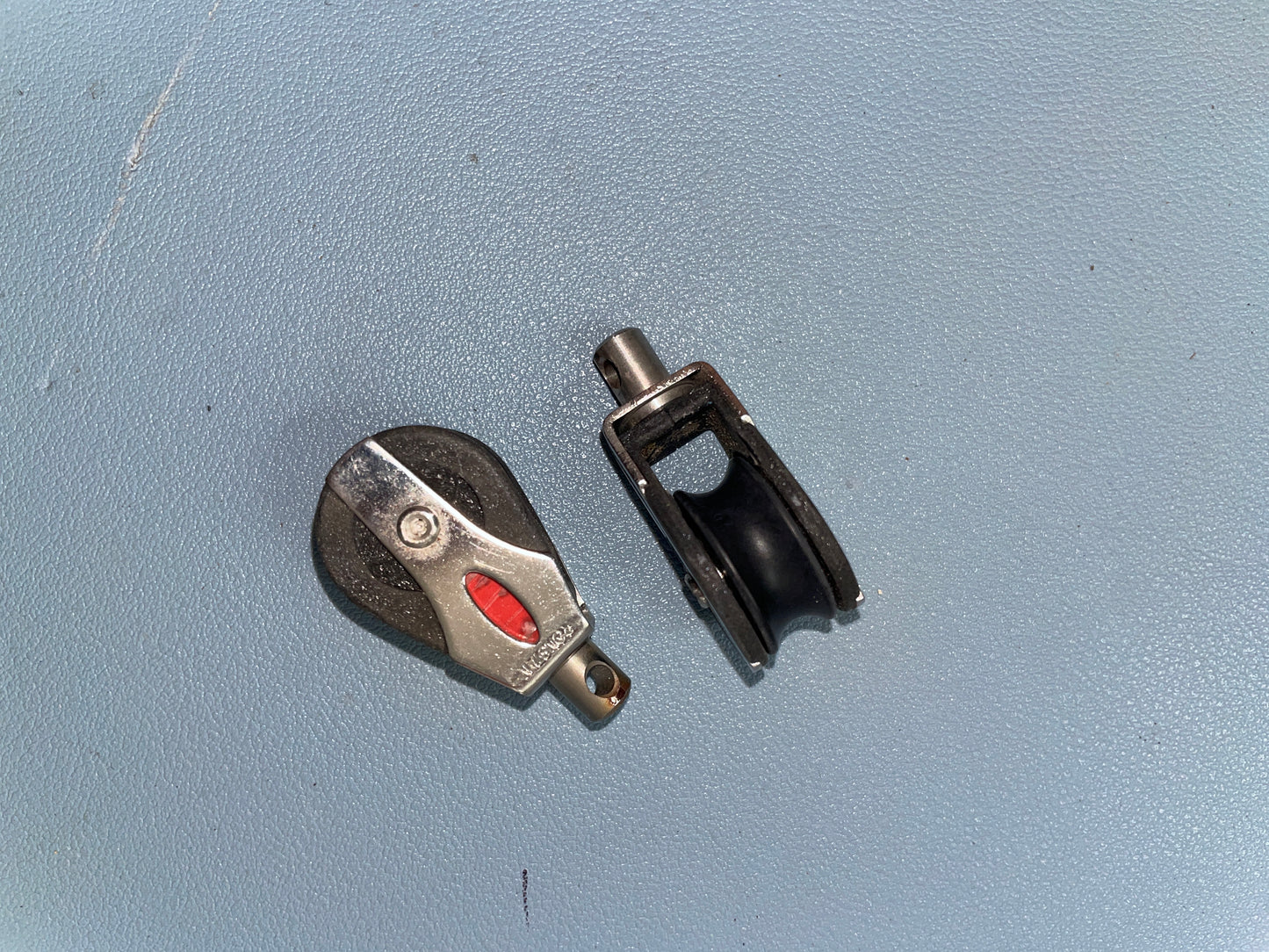 Two metal pulleys on a light blue surface