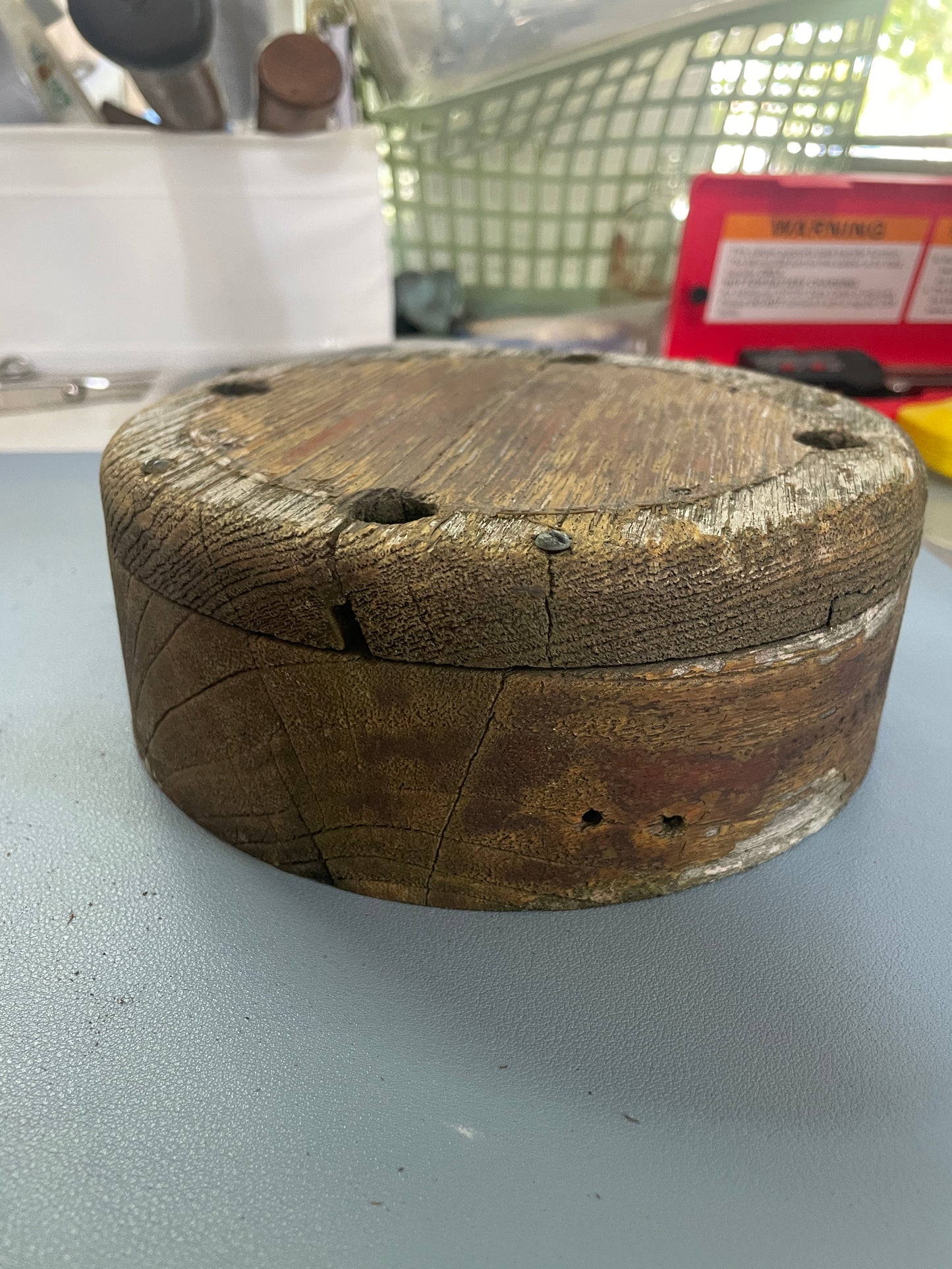 Wooden reel attached to a white wall with a blurred background