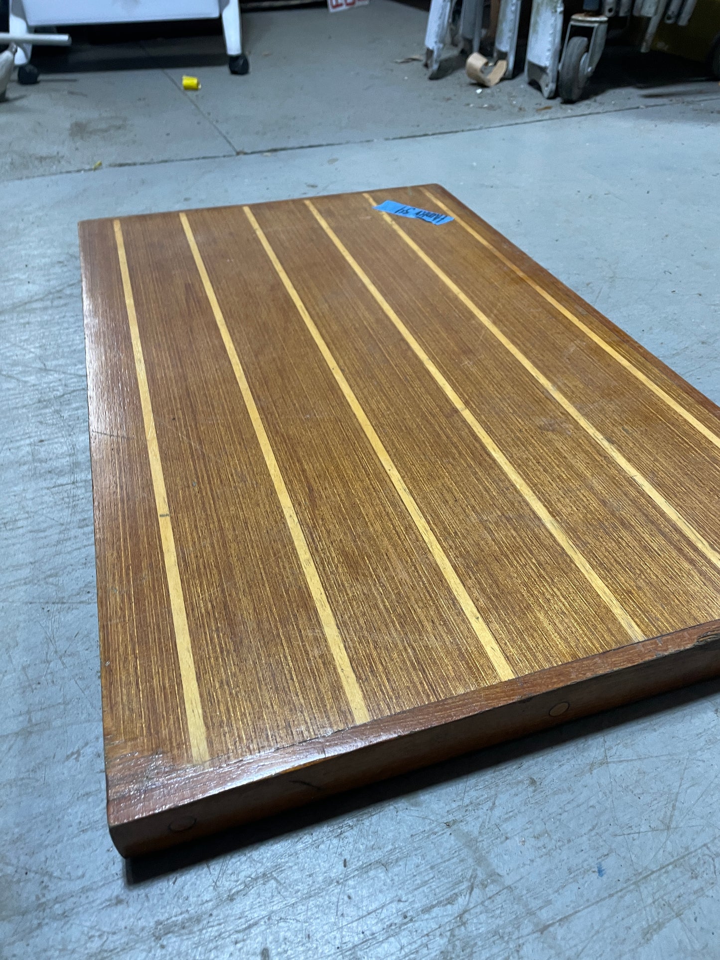 Wooden deck panel with a striped pattern on a concrete floor