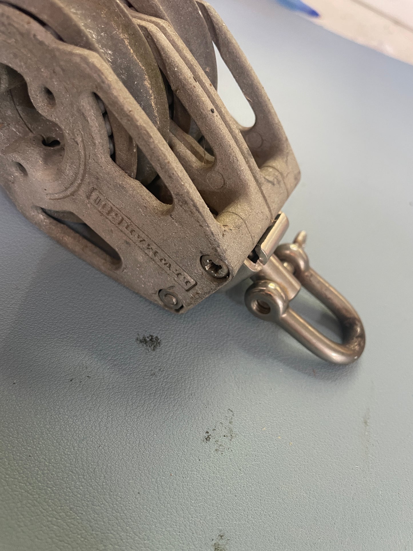Metal pulley system attached to a wall with a hook.
