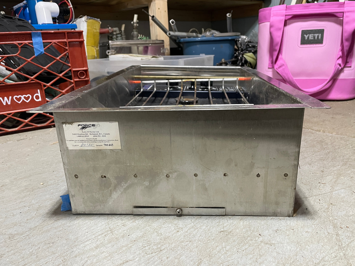 Stainless steel deep fryer on a concrete floor with a pink cooler in the background