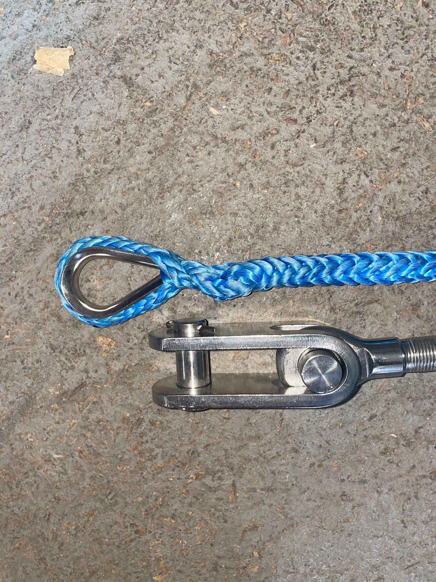 Metal shackle with blue rope on a concrete surface