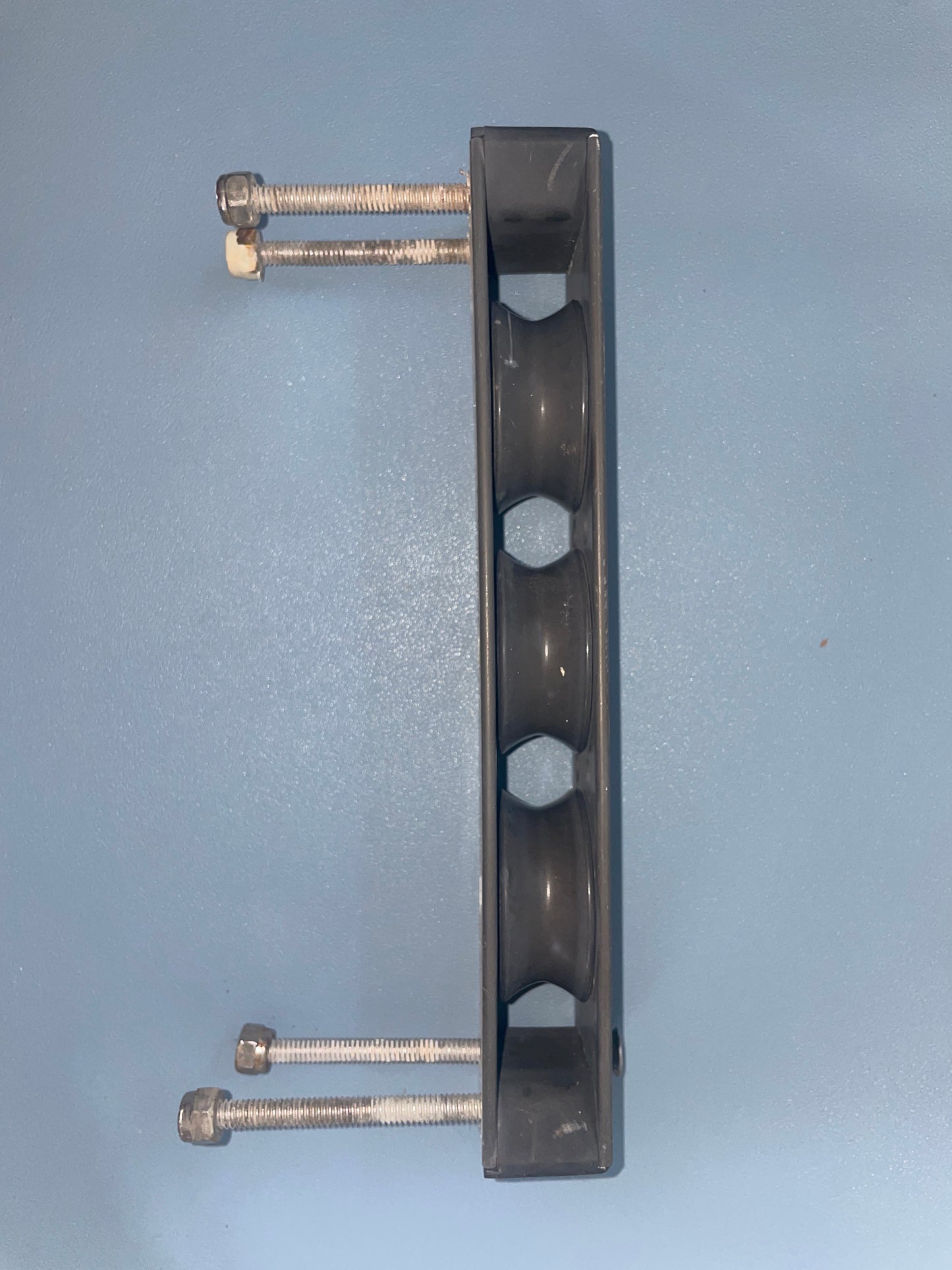 Metal bracket with four holes and bolts on a light blue background