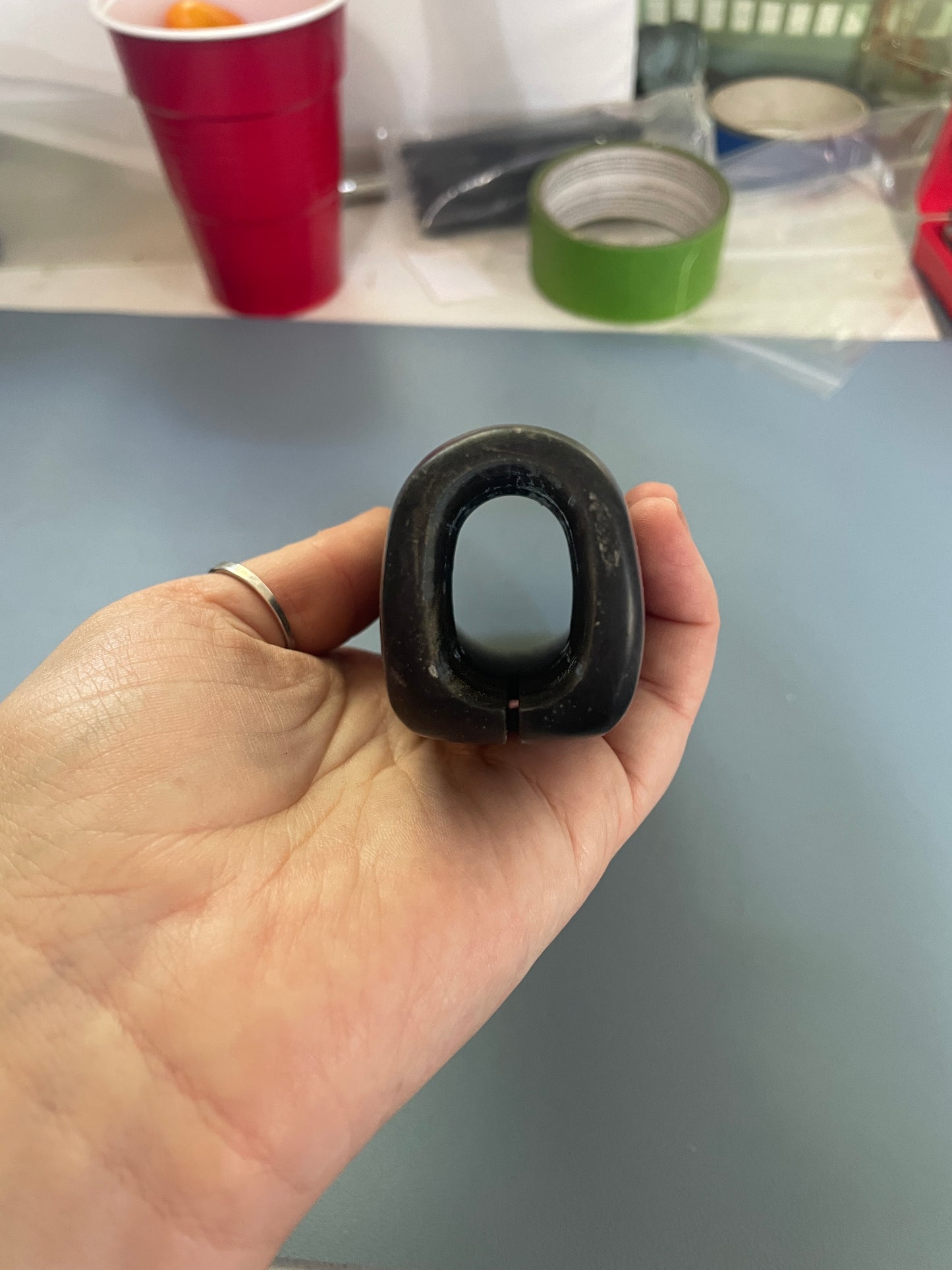 Hand holding a black rubber gasket against a blurred background