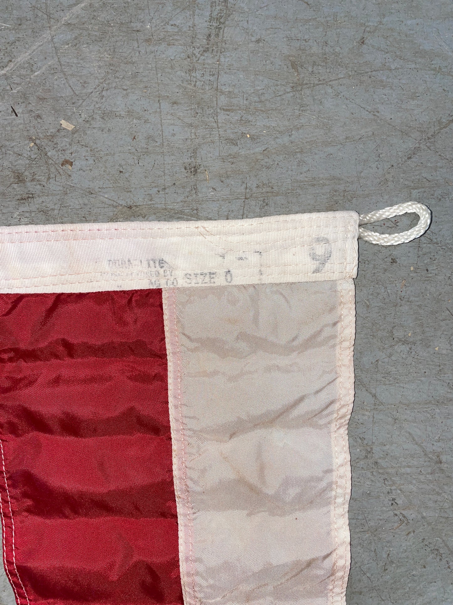 Close-up of a red and white flag with a metal ring on a textured gray background
