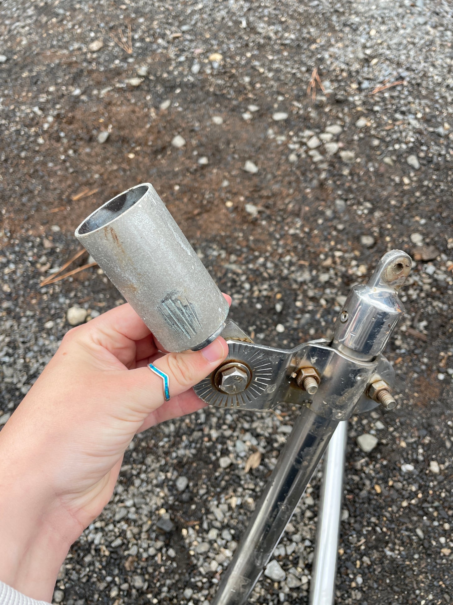 Hand holding a metal spray nozzle on a concrete surface