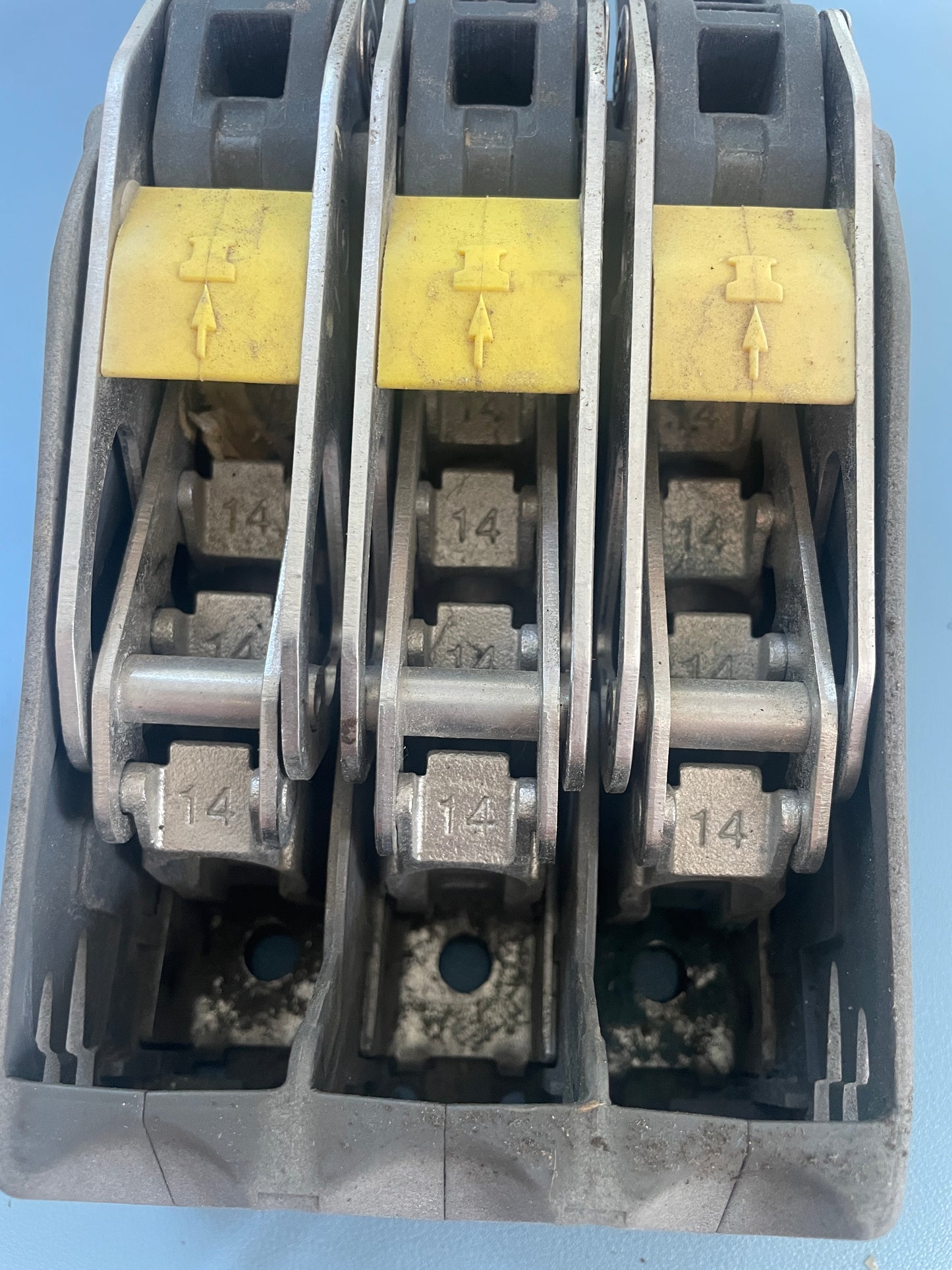Close-up of a mechanical component with metal links and yellow labels on a blue background