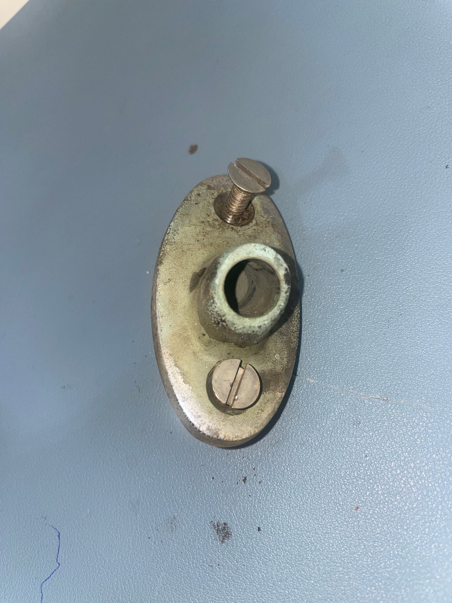 Metallic object with two screws on a light gray background