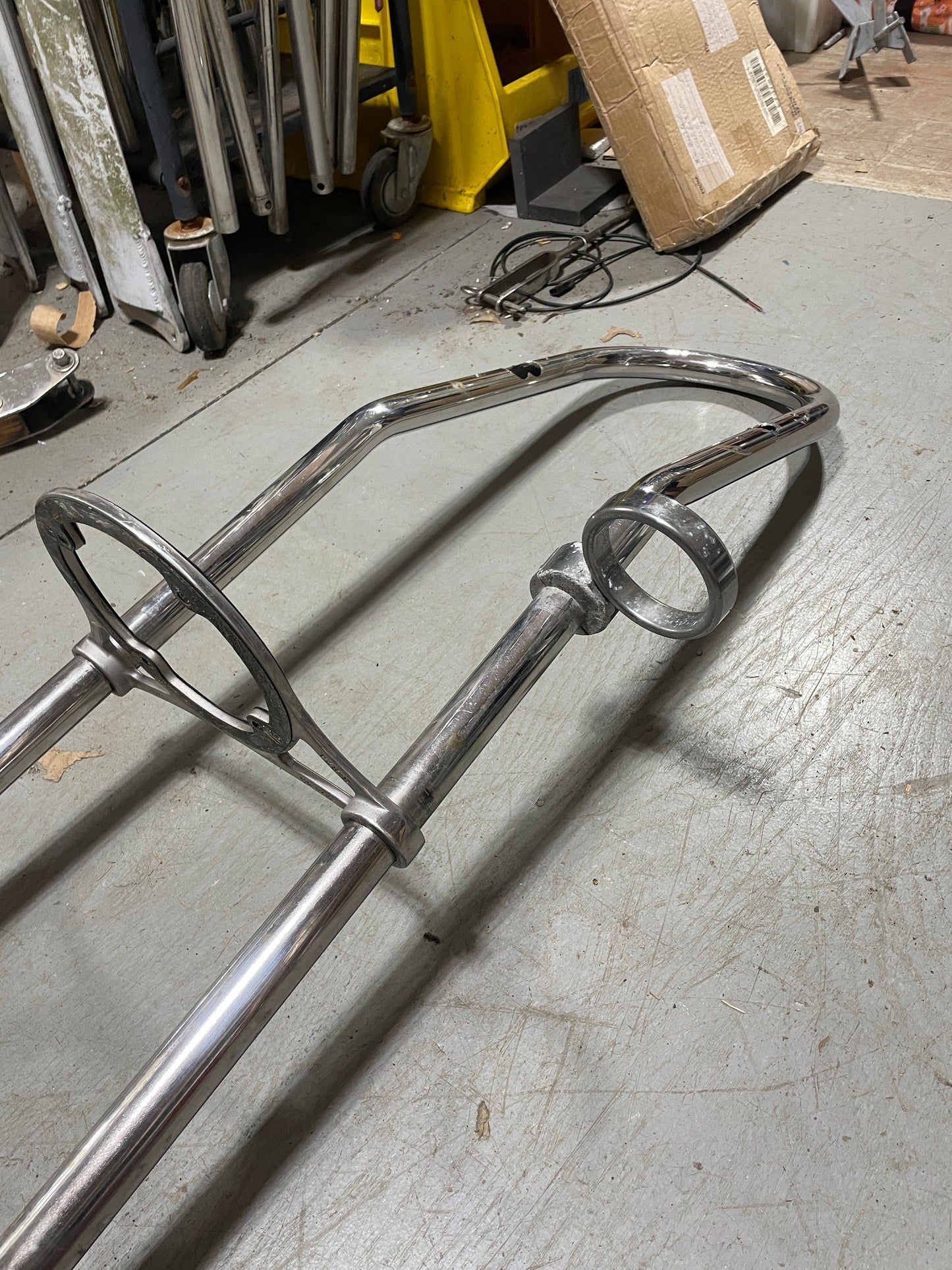 Metal bike rack on a concrete floor with tools and equipment in the background