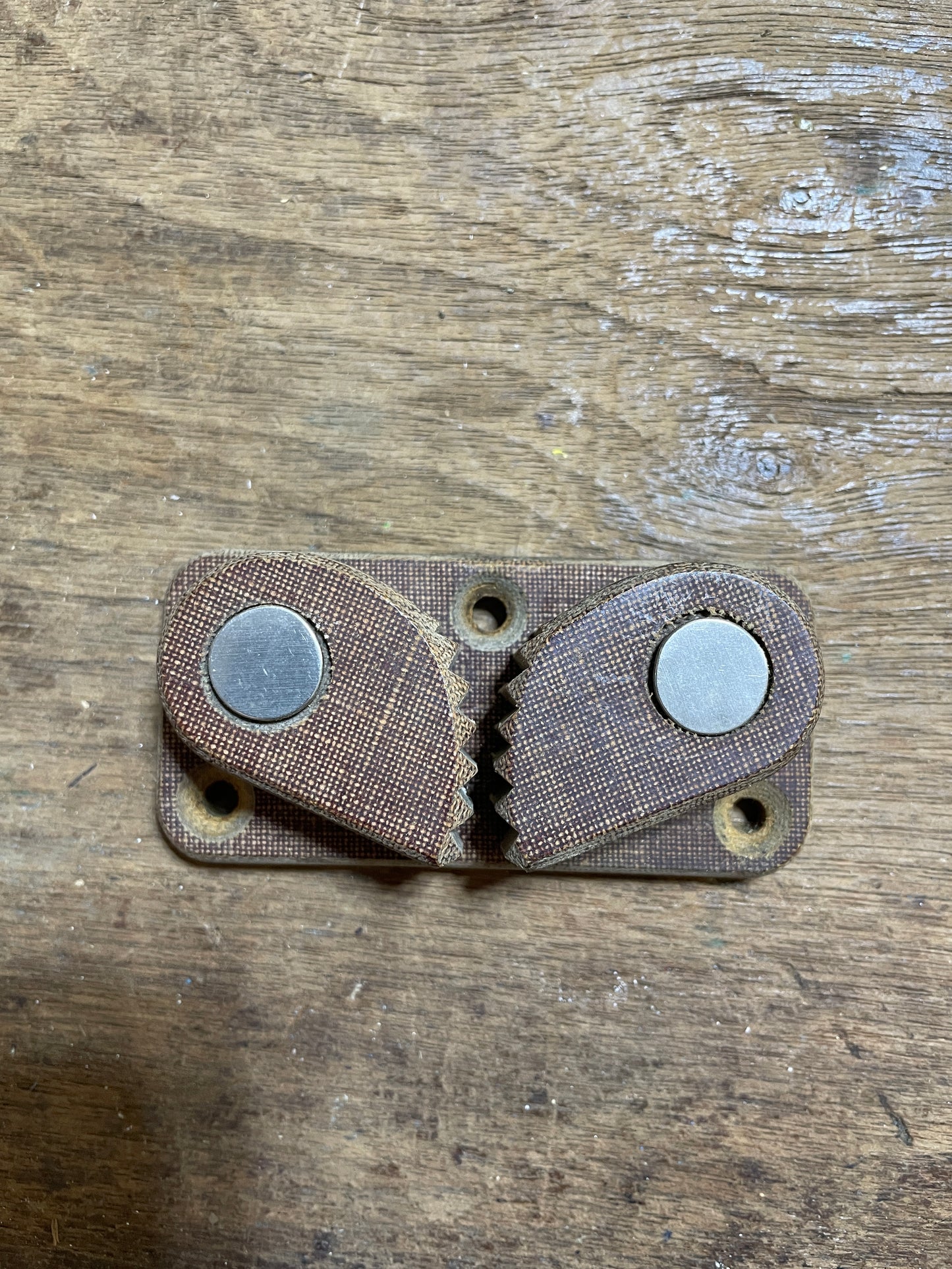 Brown leather wallet with metal fasteners on a wooden surface