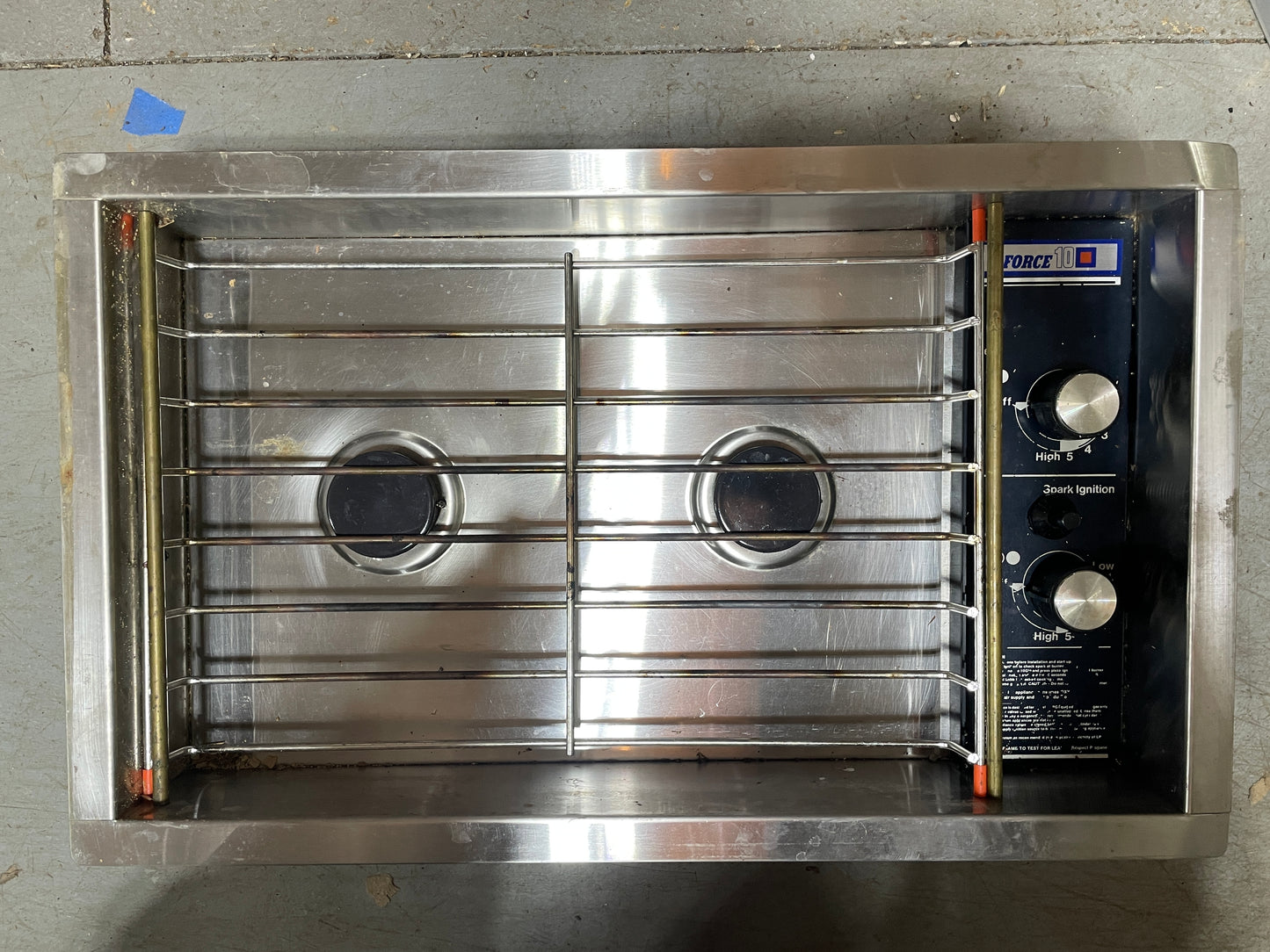 Stainless steel commercial oven with two burners on a concrete floor