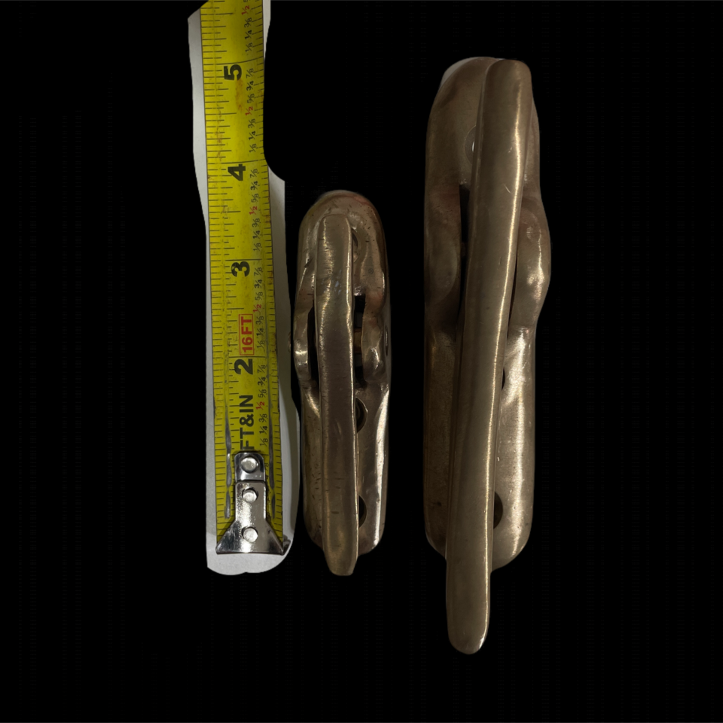 Two metallic cleats with a measuring tape on a black background