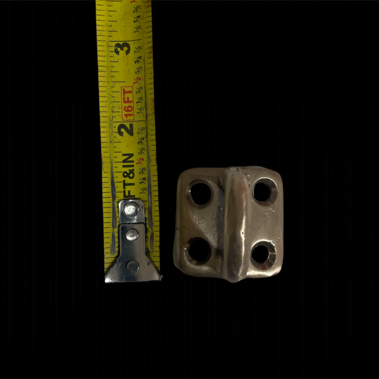 Metallic bracket with measurement tape on a black background